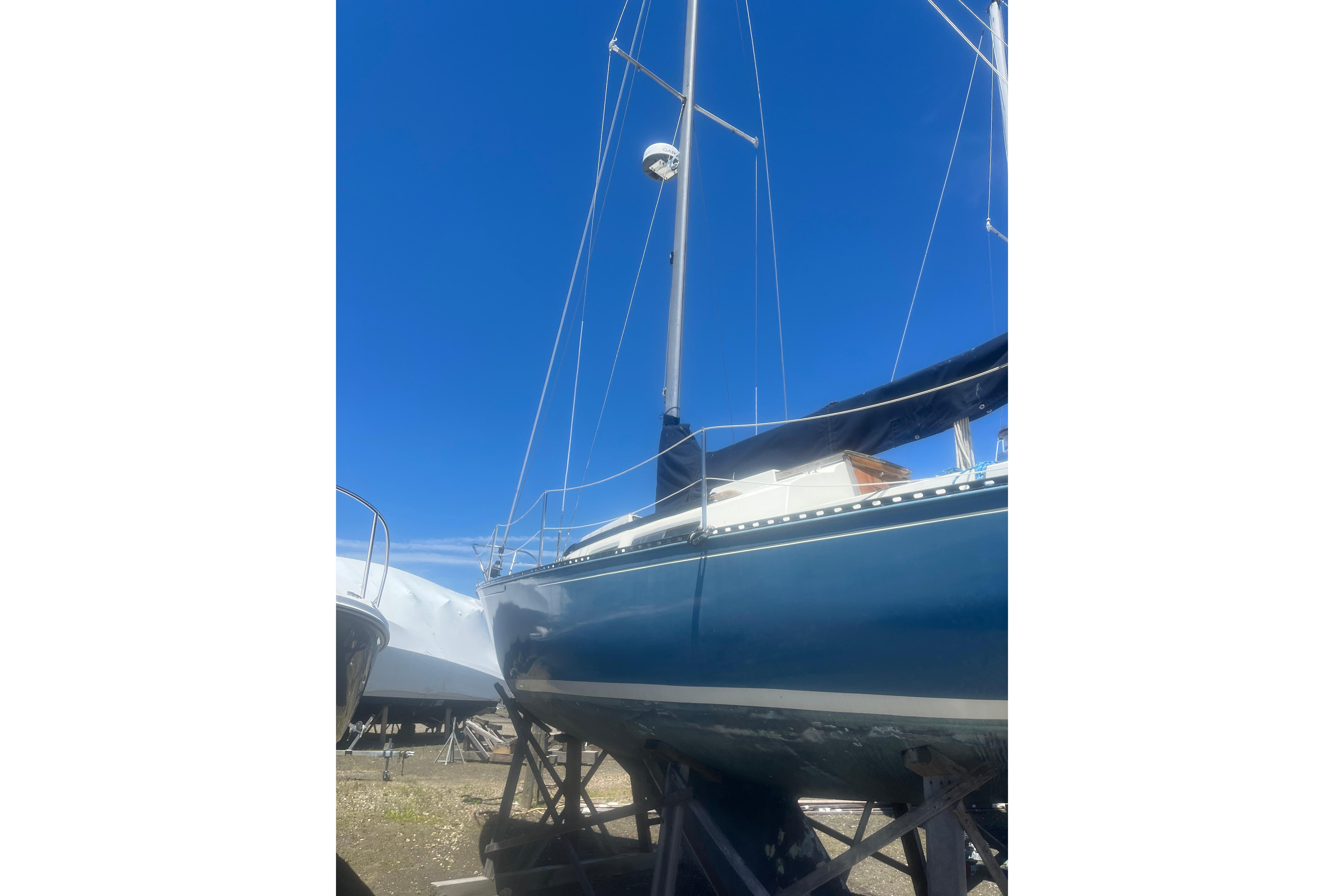 1972 C&C 30 sailboat on stands under a clear blue sky.