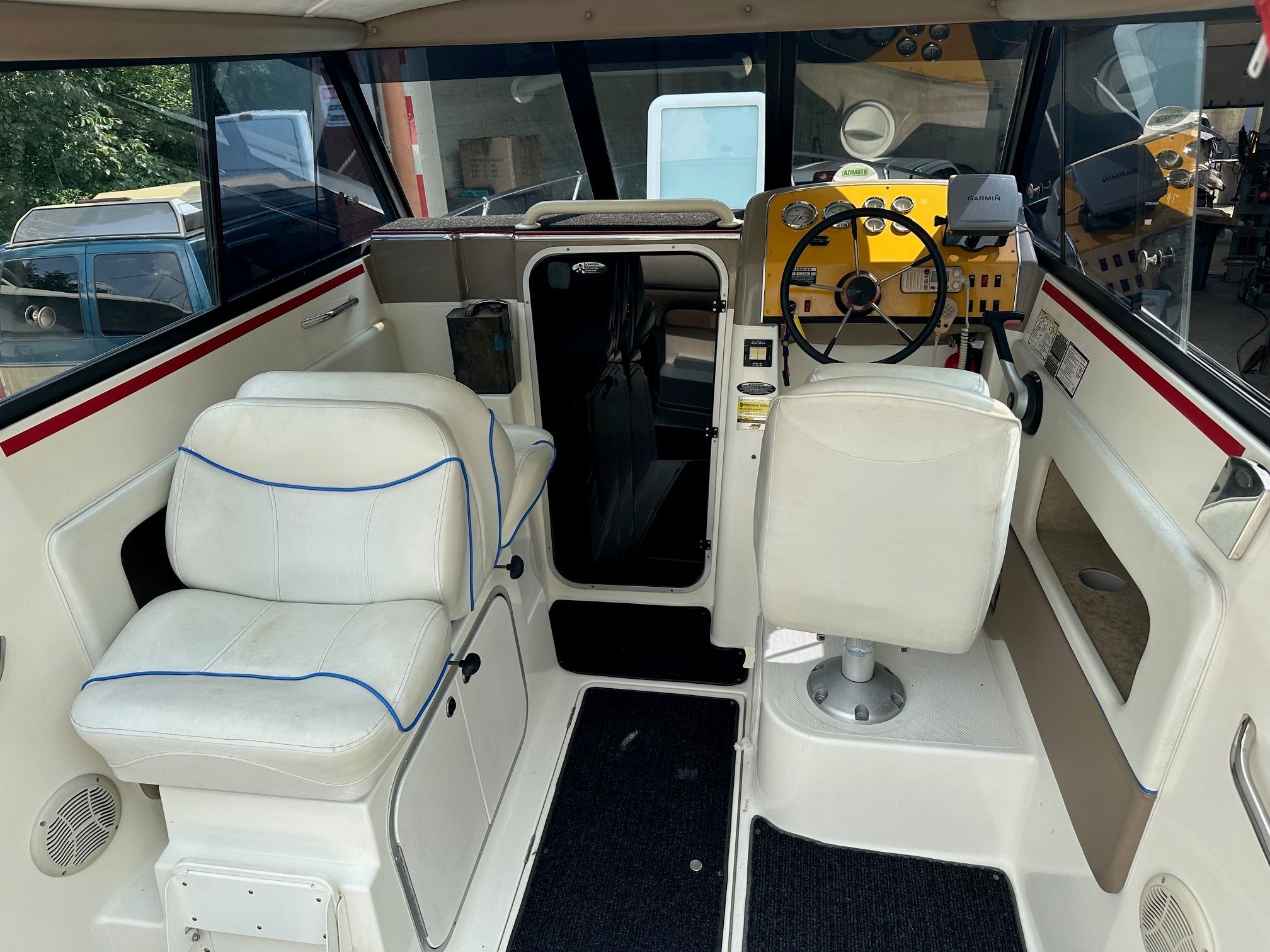 Interior of a Bayliner Sierra boat with white seats and a yellow dashboard.