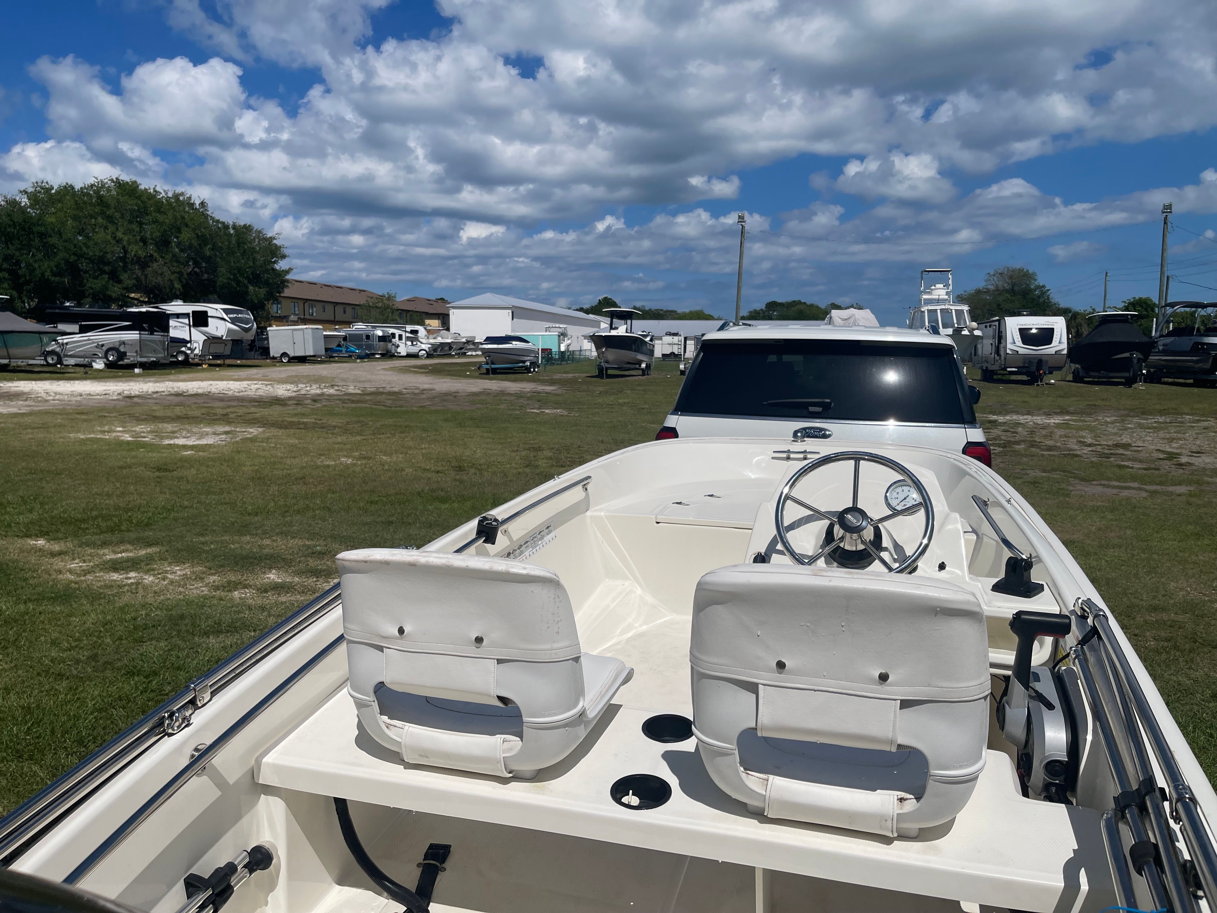 A 2017 Boston Whaler 130 Super Sport on a trailer in a grassy area.