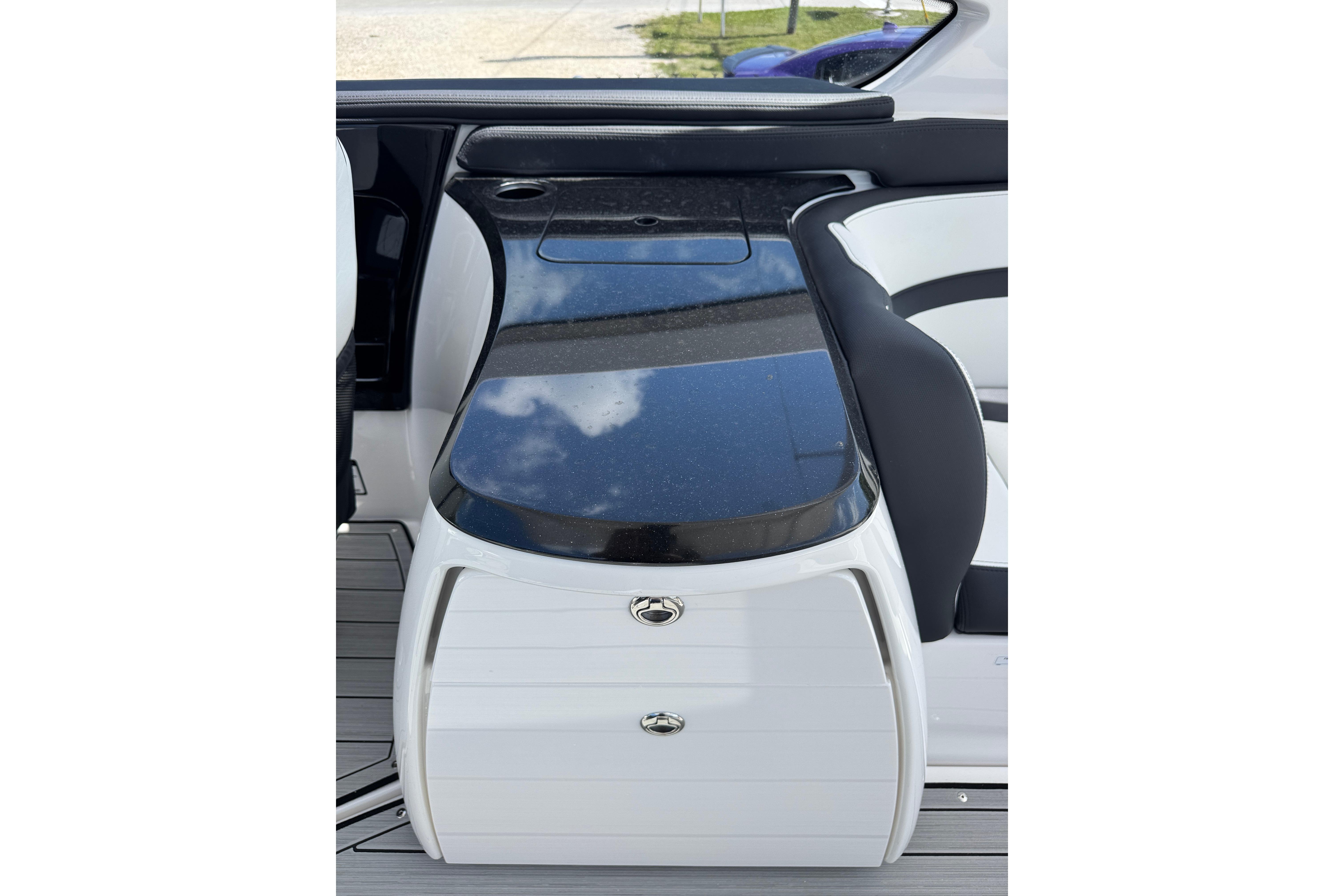 Interior view of 2026 Yamaha Boats 275SD, featuring sleek black and white seating and storage.