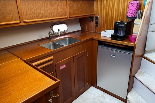 Interior of 1998 Storebro 430 Royal Cruiser kitchen with wood cabinetry and modern appliances.