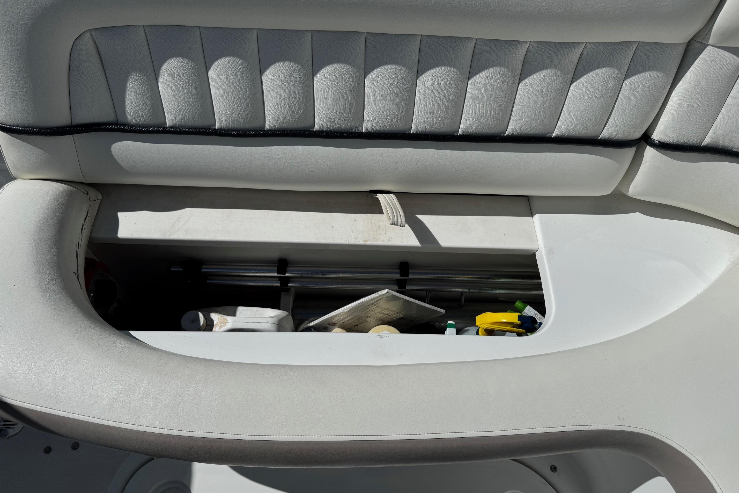 Open storage compartment in a 2005 Cobalt 240 boat with various items inside.