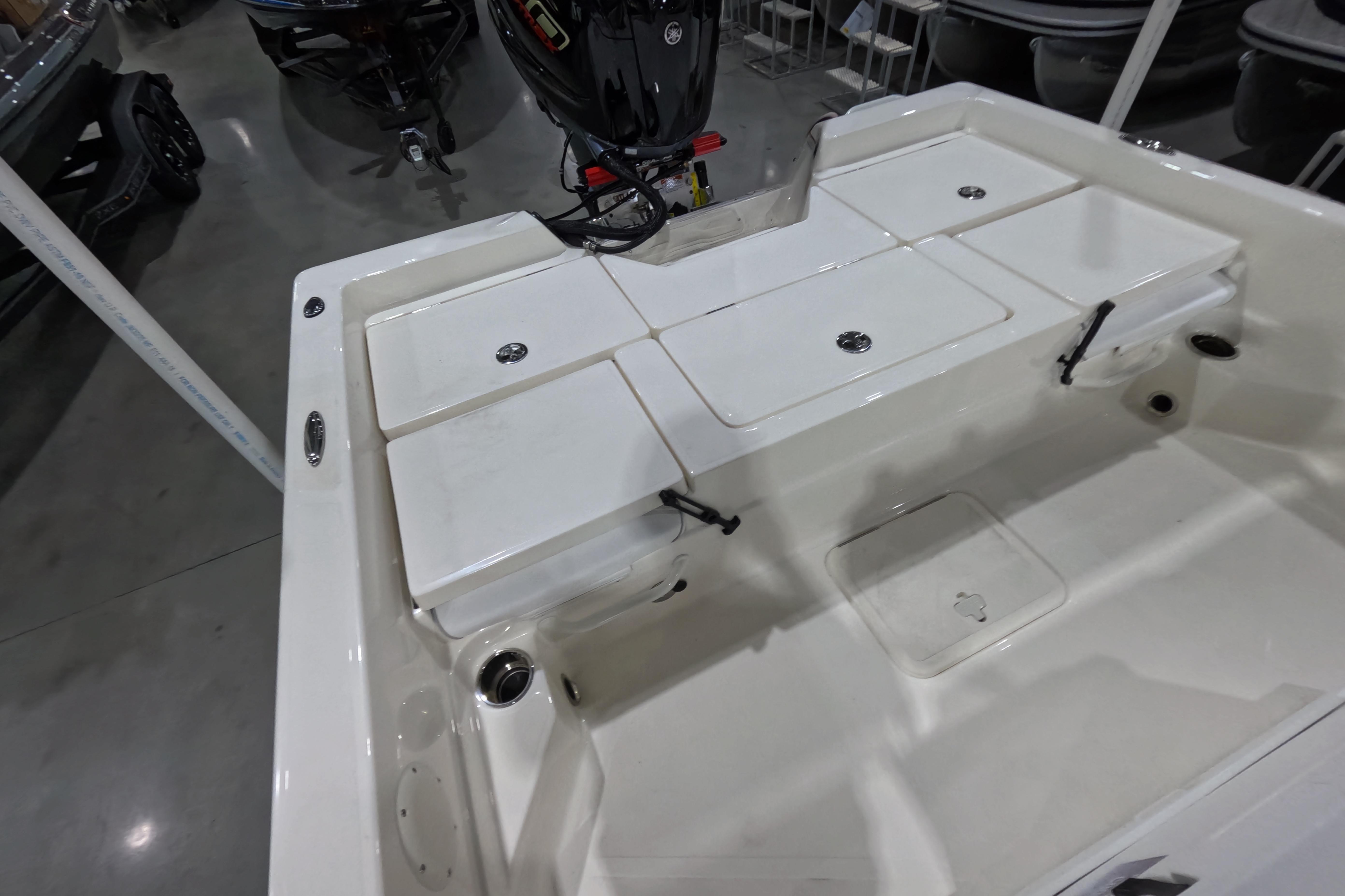 2026 Skeeter SX230 boat interior with storage compartments and motor in showroom.