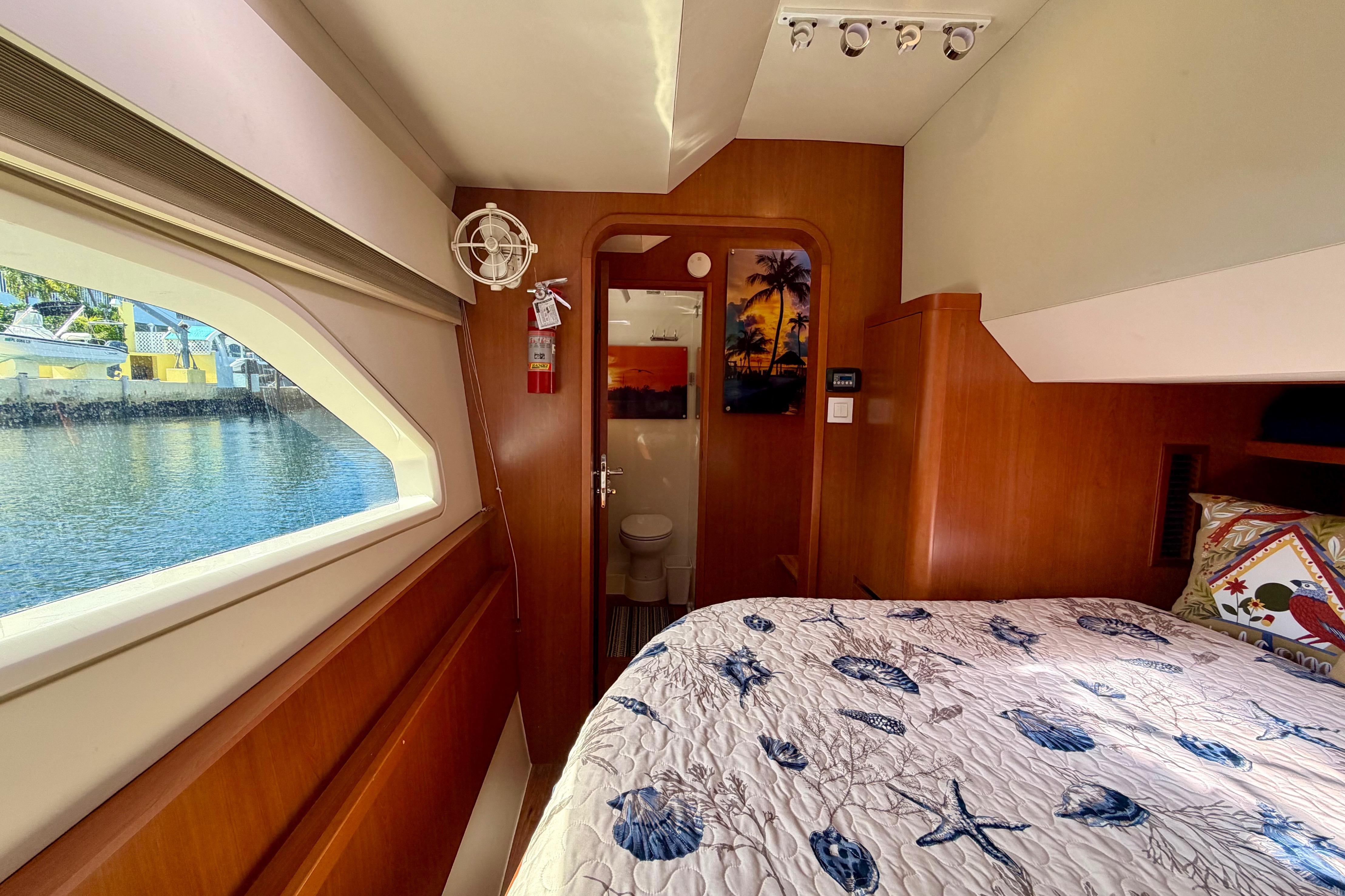 Interior of 2017 Aquila 44 Yacht cabin with bed, window view, and wooden decor.