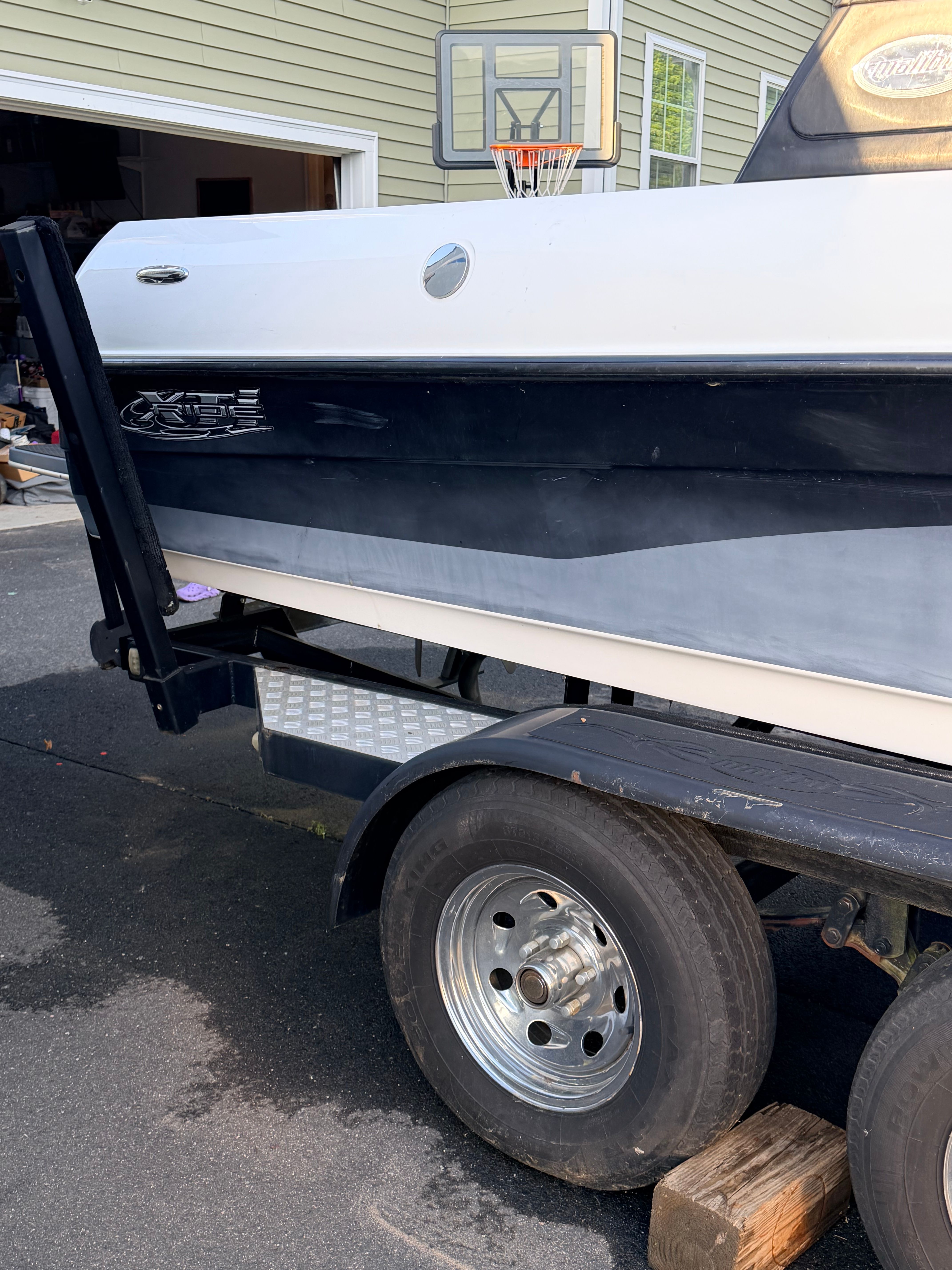 2006 Malibu iRide boat on trailer parked in driveway.