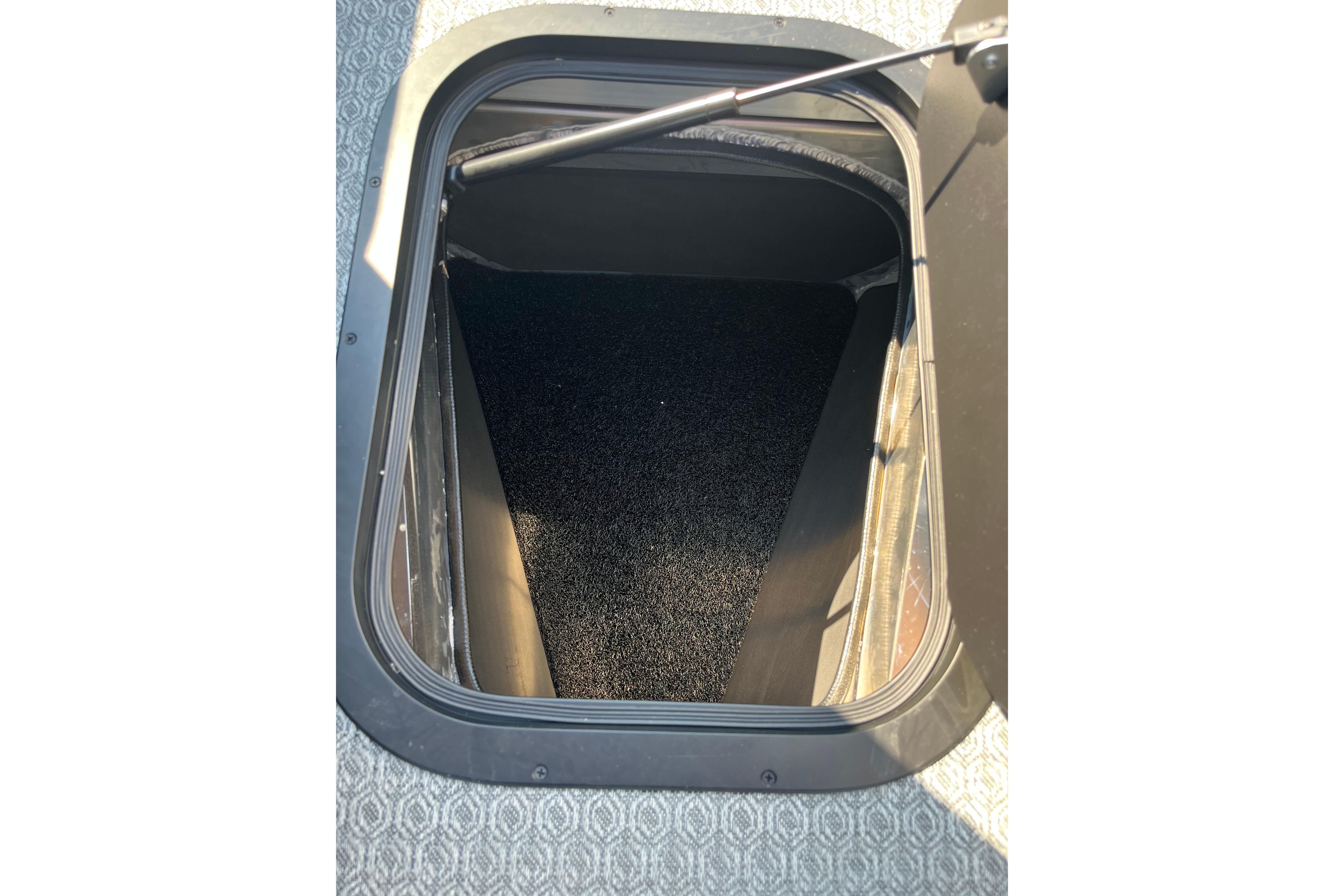 Open storage compartment in 2026 Evotti 725CS vehicle, featuring a carpeted interior.