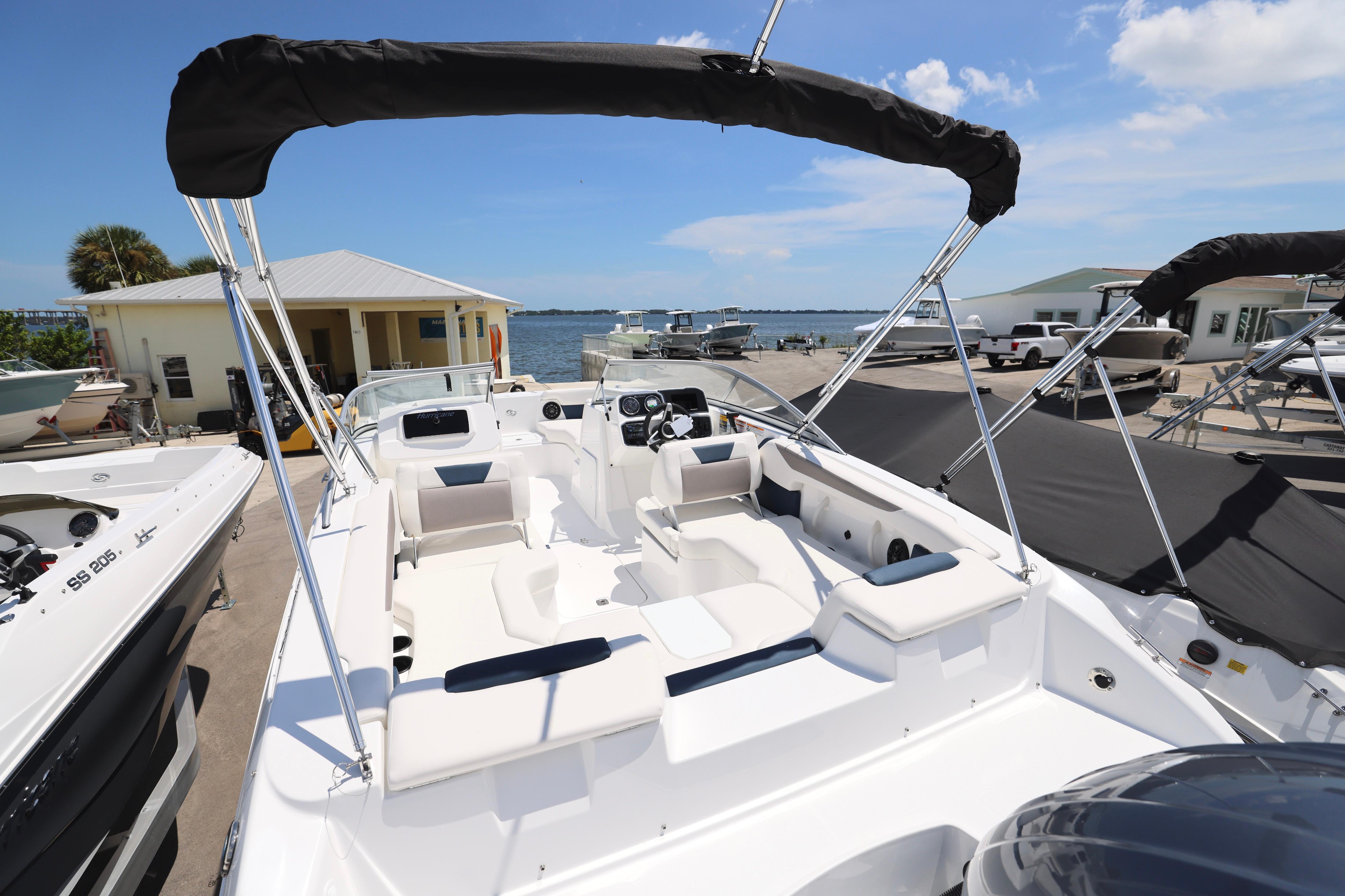2026 Hurricane SunDeck 2050 OB boat with spacious seating and canopy, docked near waterfront.