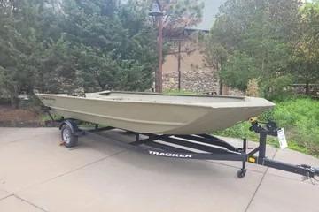 2025 Tracker GRIZZLY 2072 Utility boat on trailer, outdoors with trees in background.