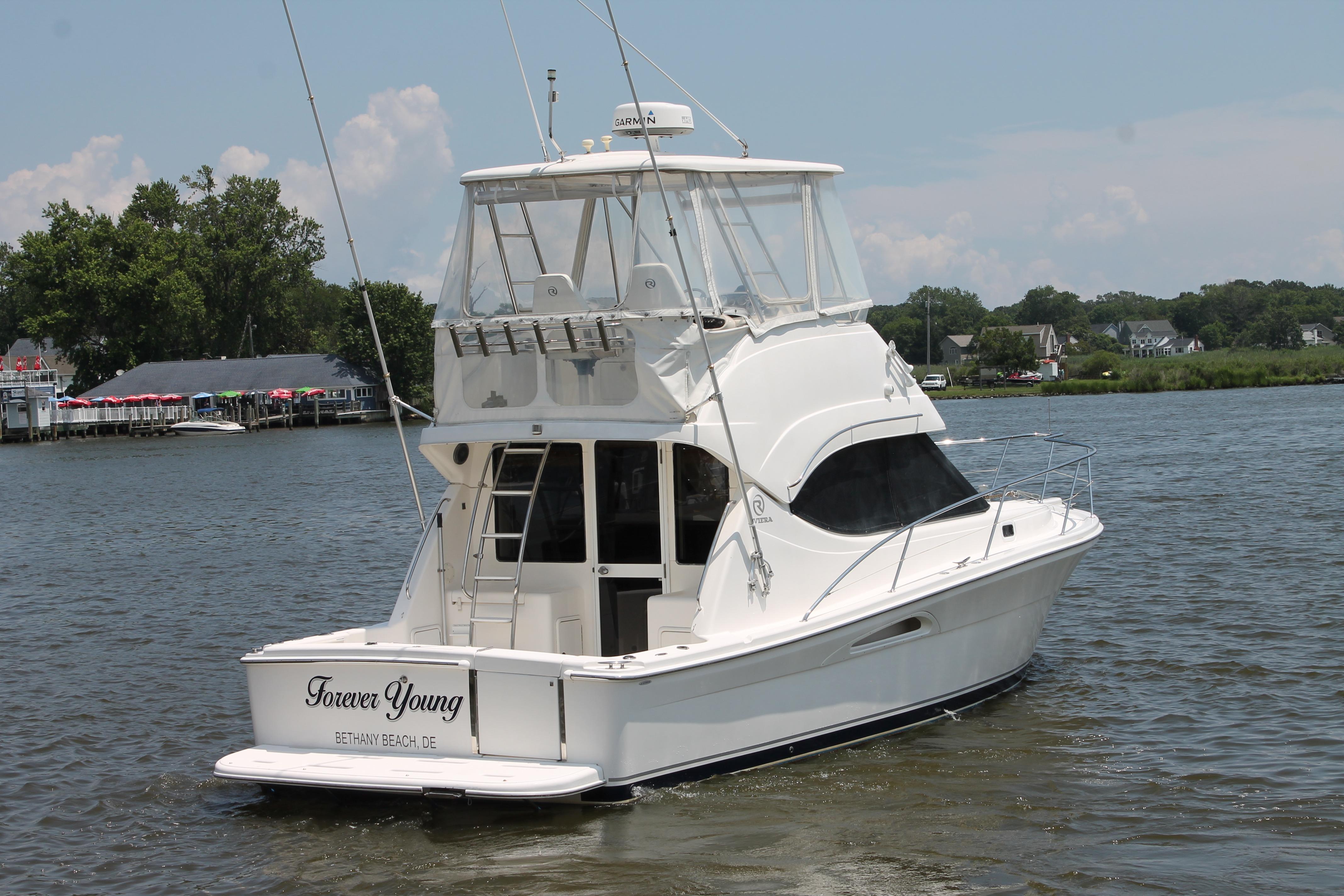 2007 Riviera 33 Flybridge yacht named "Forever Young" on a serene river.