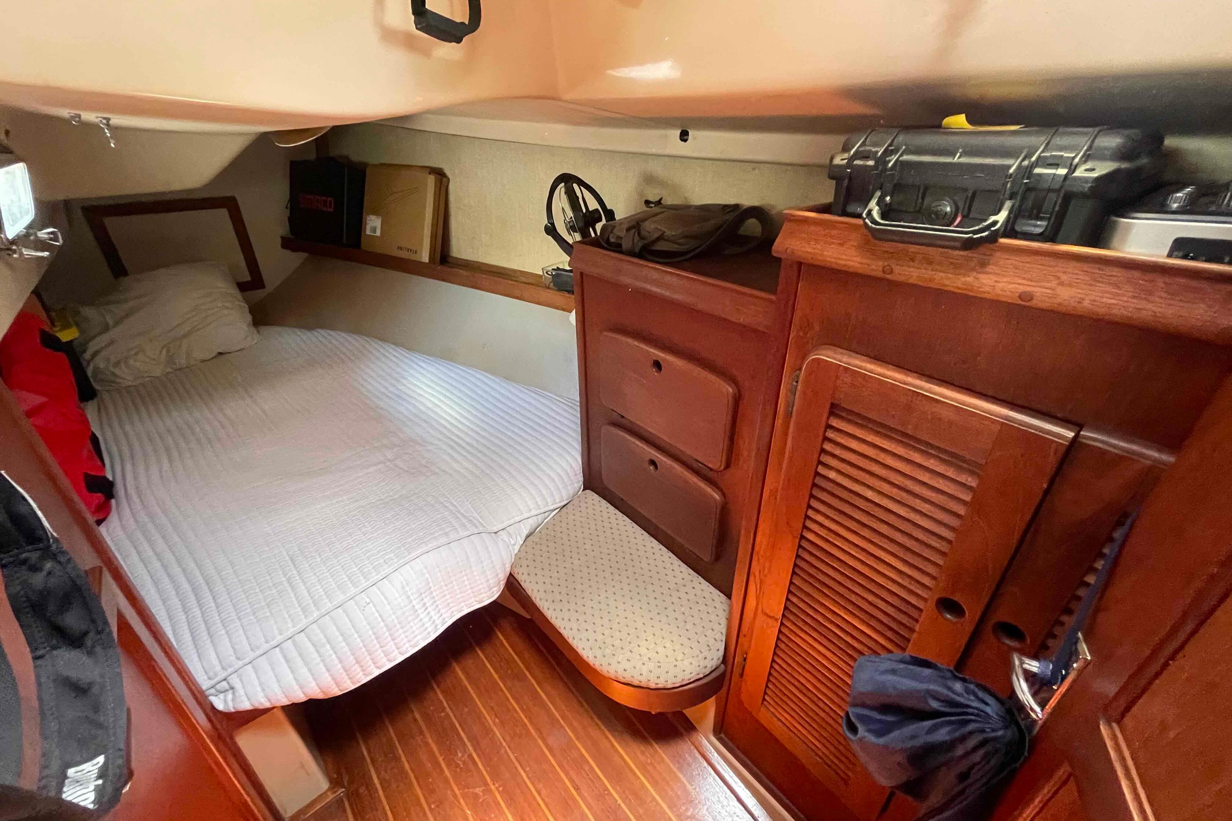 Cozy cabin interior of 1989 Island Packet 35 sailboat with wooden furnishings and bed.
