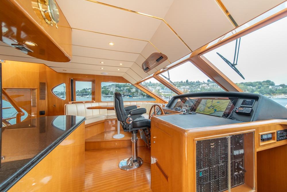 Luxurious 2005 Ocean Alexander 64 Motoryacht helm with panoramic windows and elegant wood finish.