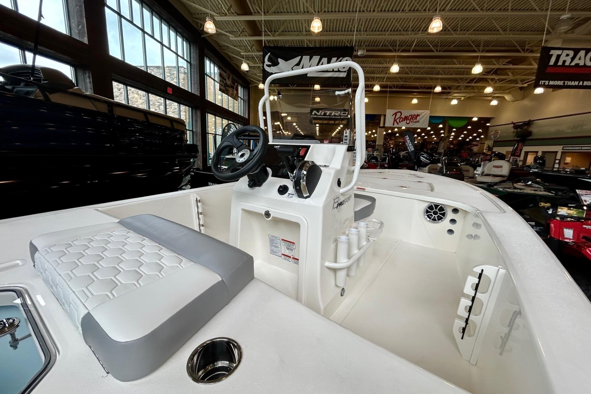 2026 Mako Pro Skiff 18 boat interior in showroom, featuring steering console and seating.