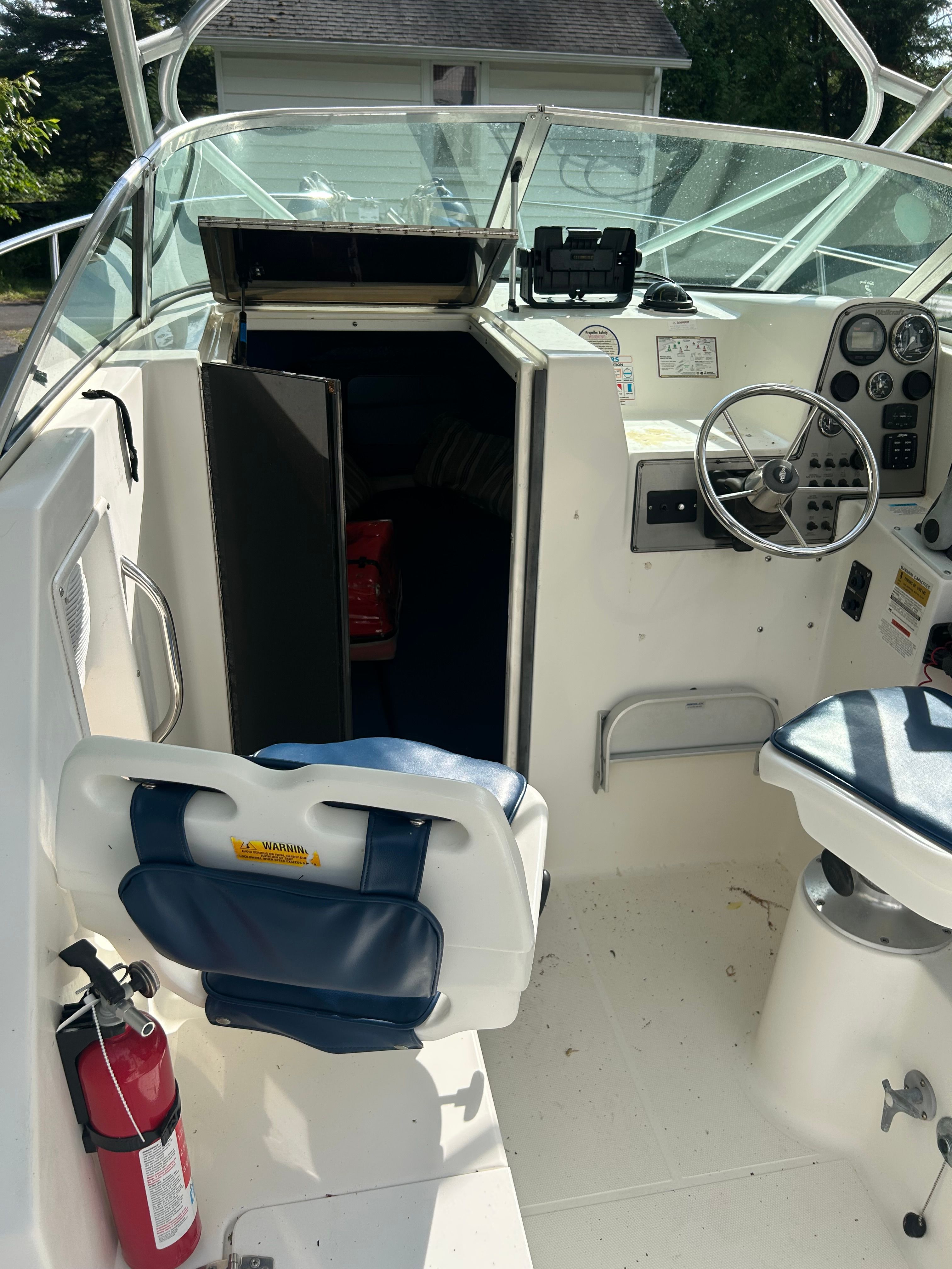 The image shows the cockpit of a 2002 Wellcraft 24 Walkaround boat with helm and seating.