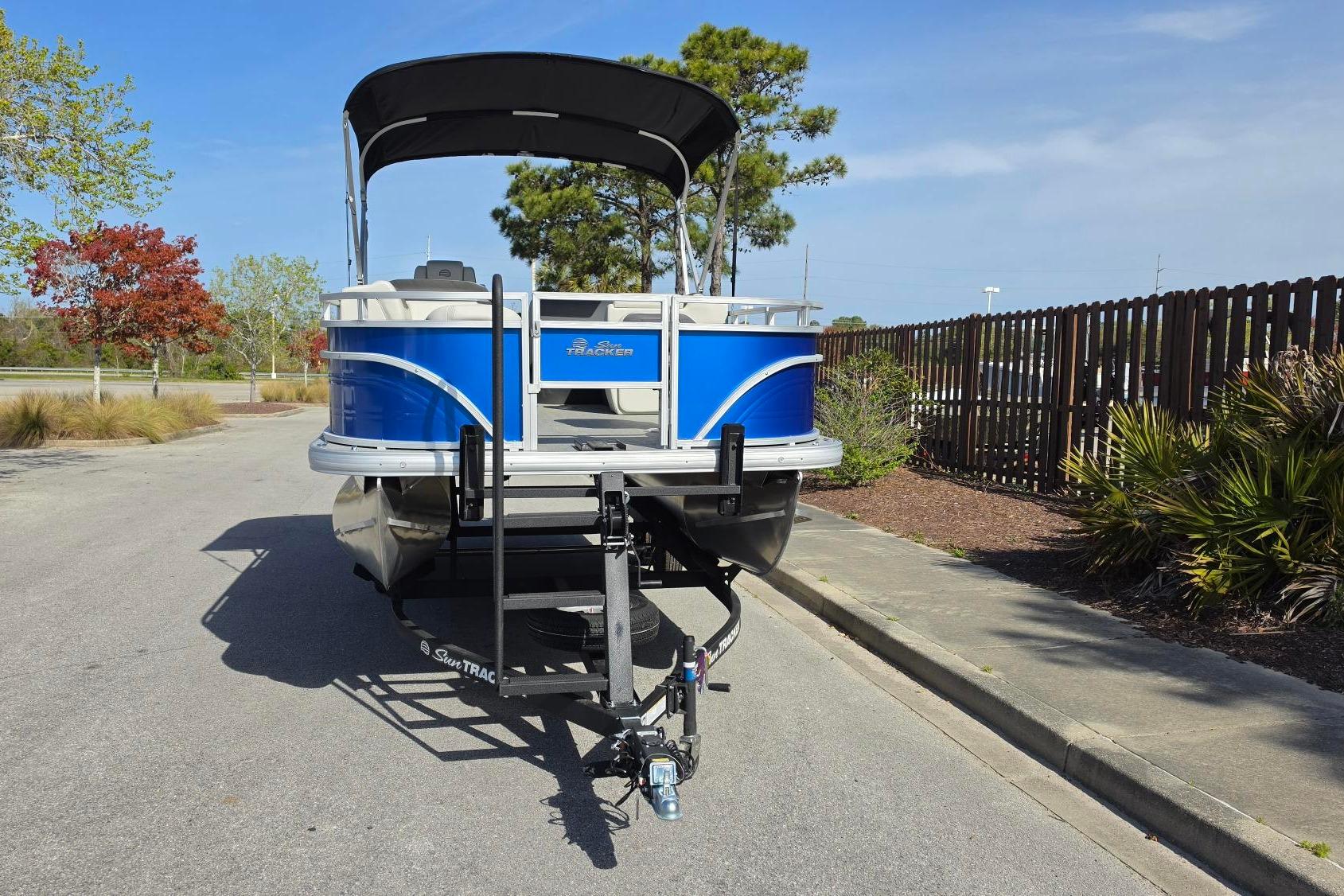 2026 Sun Tracker Fishin' Barge 20 DLX on trailer, parked outdoors.
