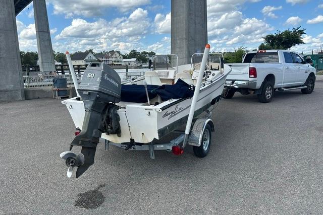 1989 Henry O 150 Dual Console boat with Evinrude motor, parked near a bridge.