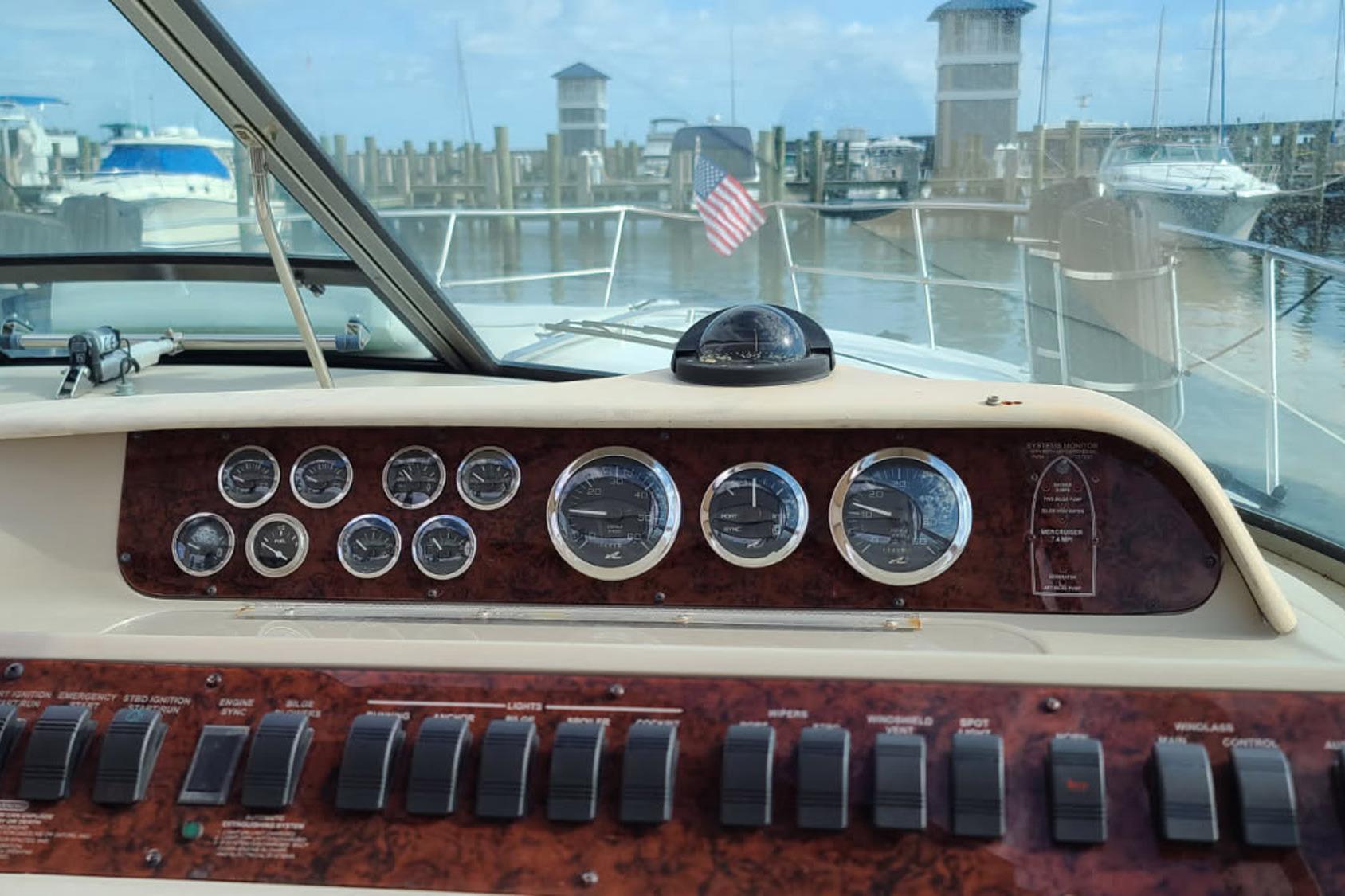 1998 Sea Ray Sundancer 400 dashboard with gauges and switches, marina view in background.