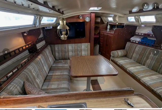 Interior of a 1982 Catalina sailboat with cozy seating and a wooden table.