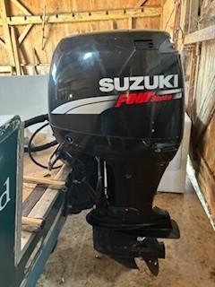 Suzuki outboard motor on 1990 Custom North End Composites Point boat in wooden shed.