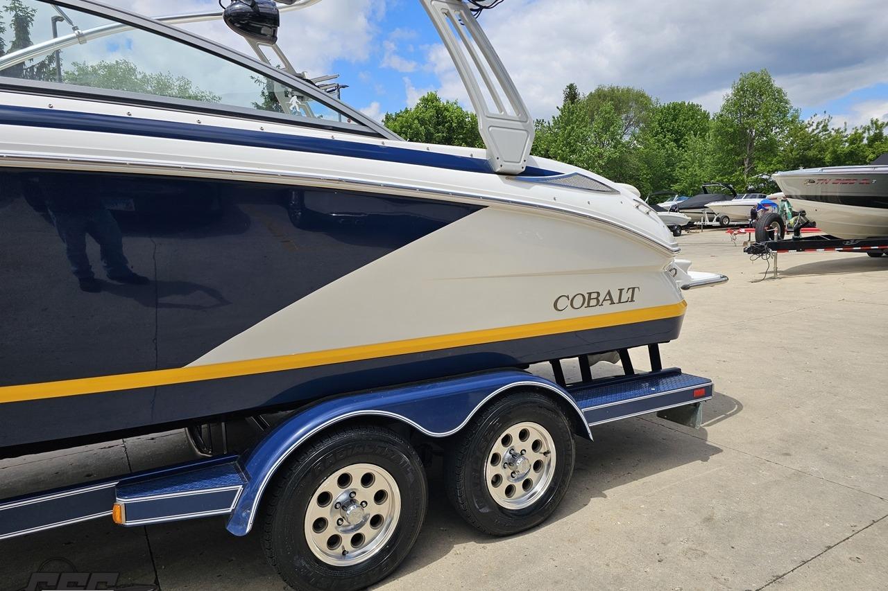 2010 Cobalt 232 WSS boat on trailer, parked outdoors under a partly cloudy sky.