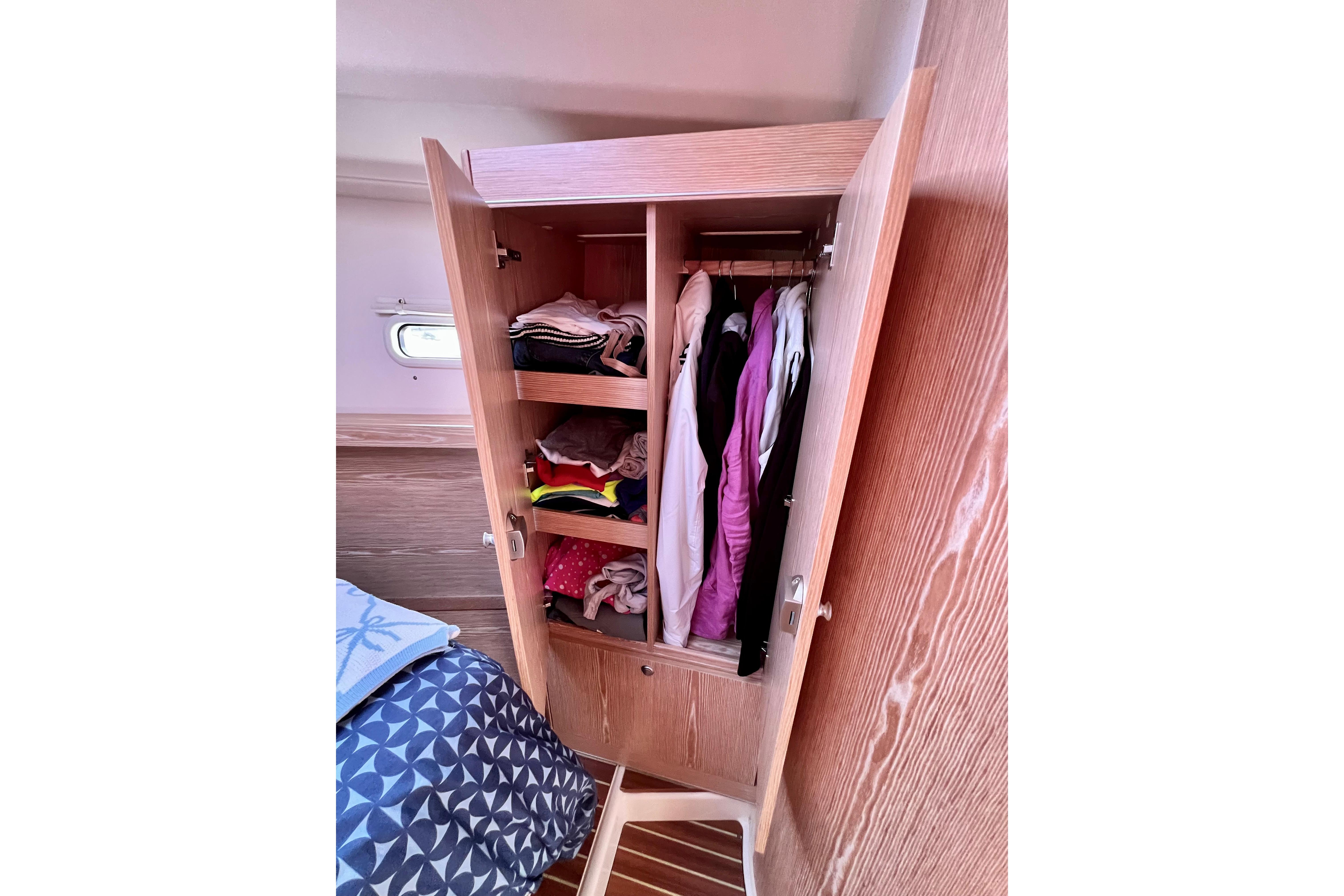 Wooden wardrobe with clothes inside a 2016 Hanse 455 yacht cabin.