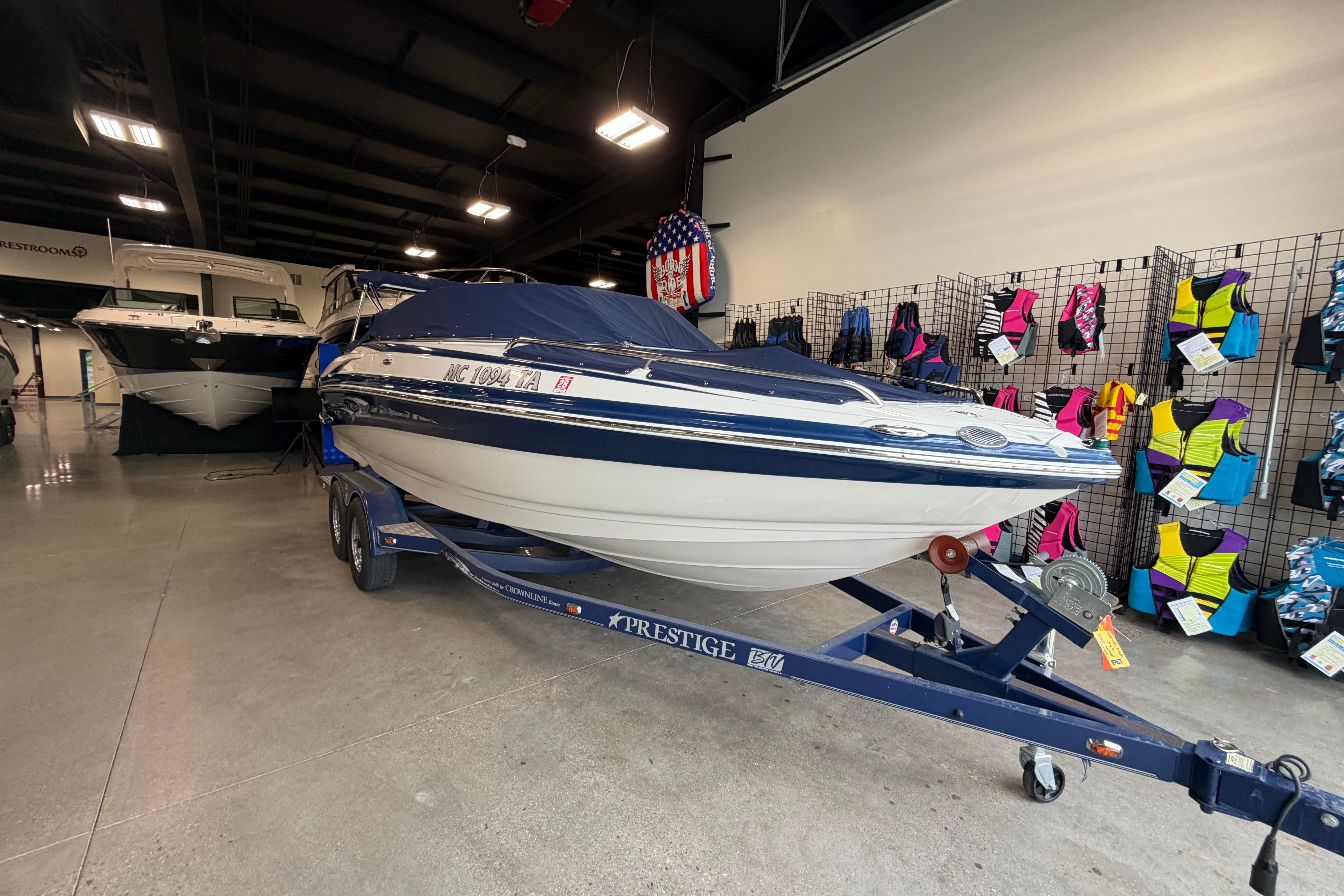 2008 Crownline 220 LS boat on trailer in showroom with life jackets displayed.