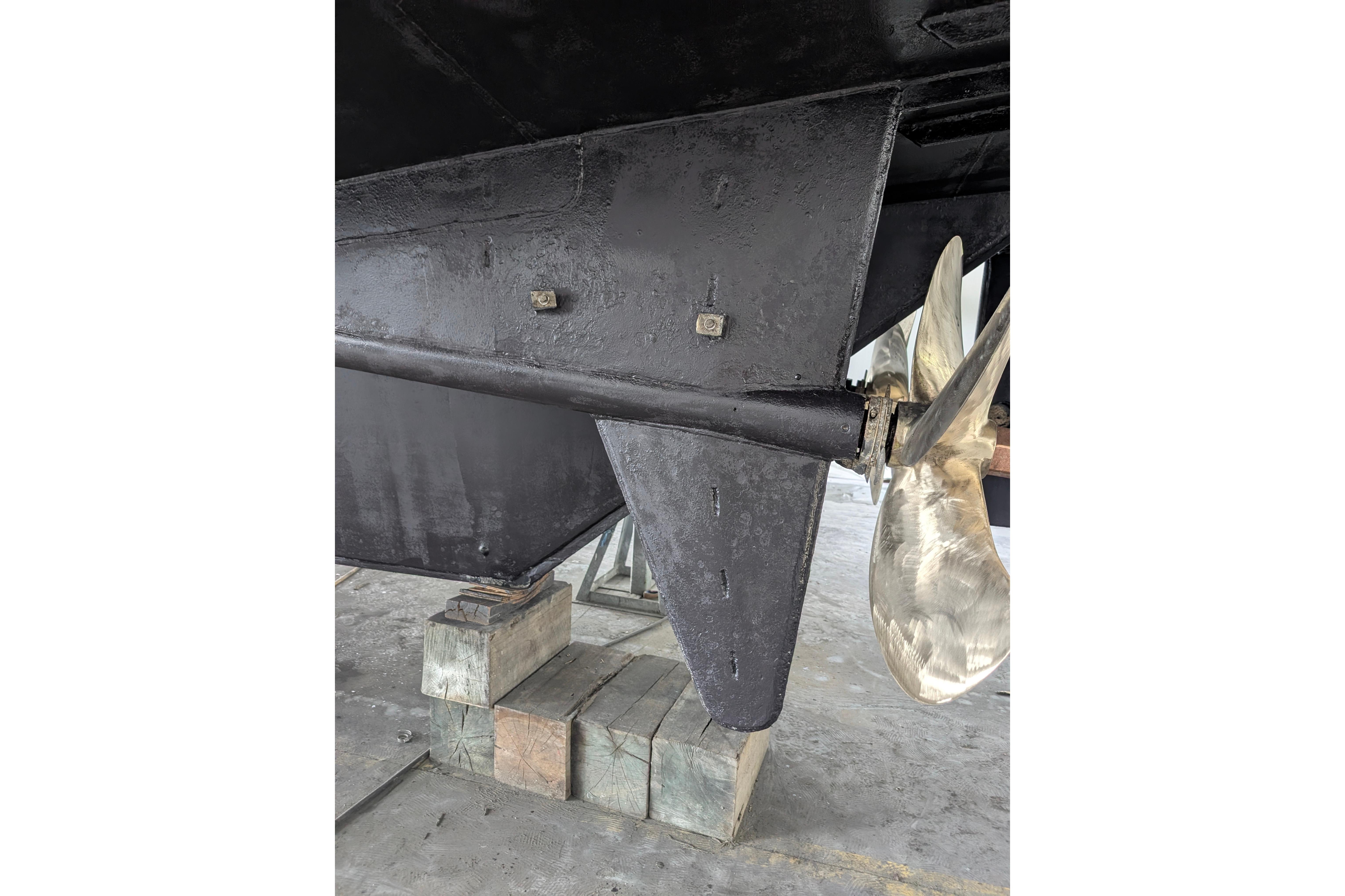Close-up of a 2001 Doggersbank yacht propeller and rudder on blocks.