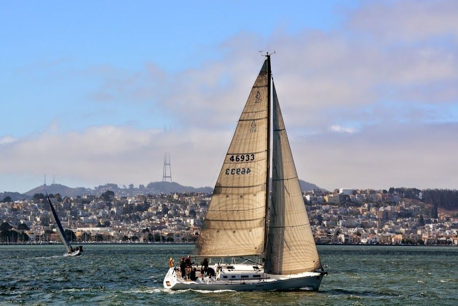 Beneteau First 40.7 sailboat from 2000 on water with cityscape background.