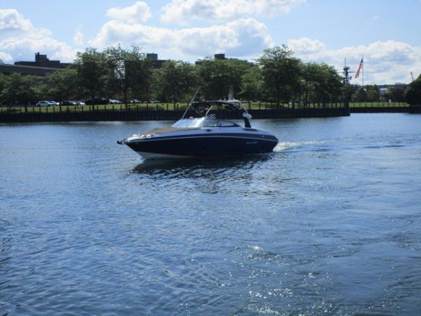 2017 Larson 292 LXI boat cruising on a calm river under a partly cloudy sky.