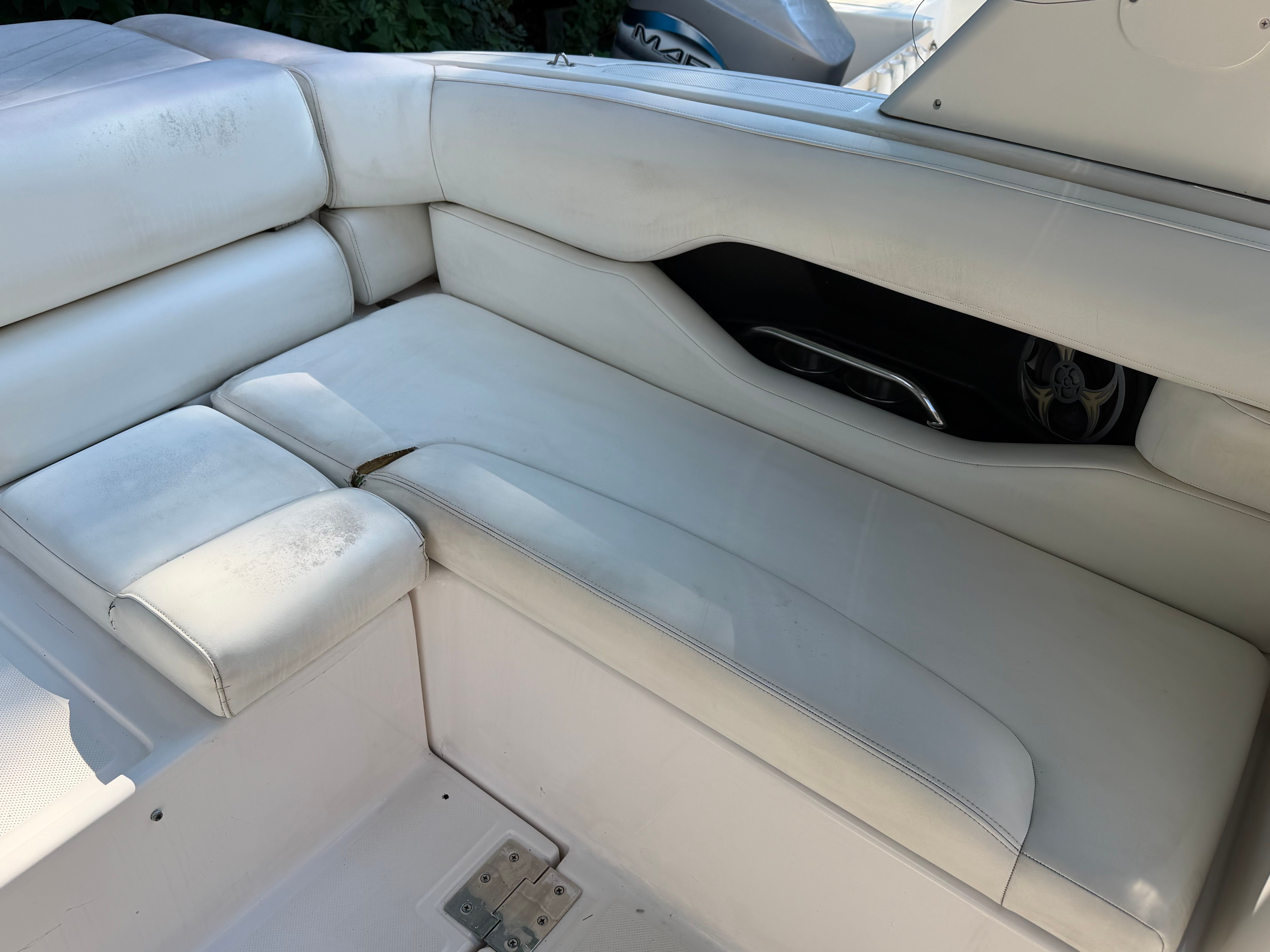 White cushioned bench in a boat with speaker and armrest.