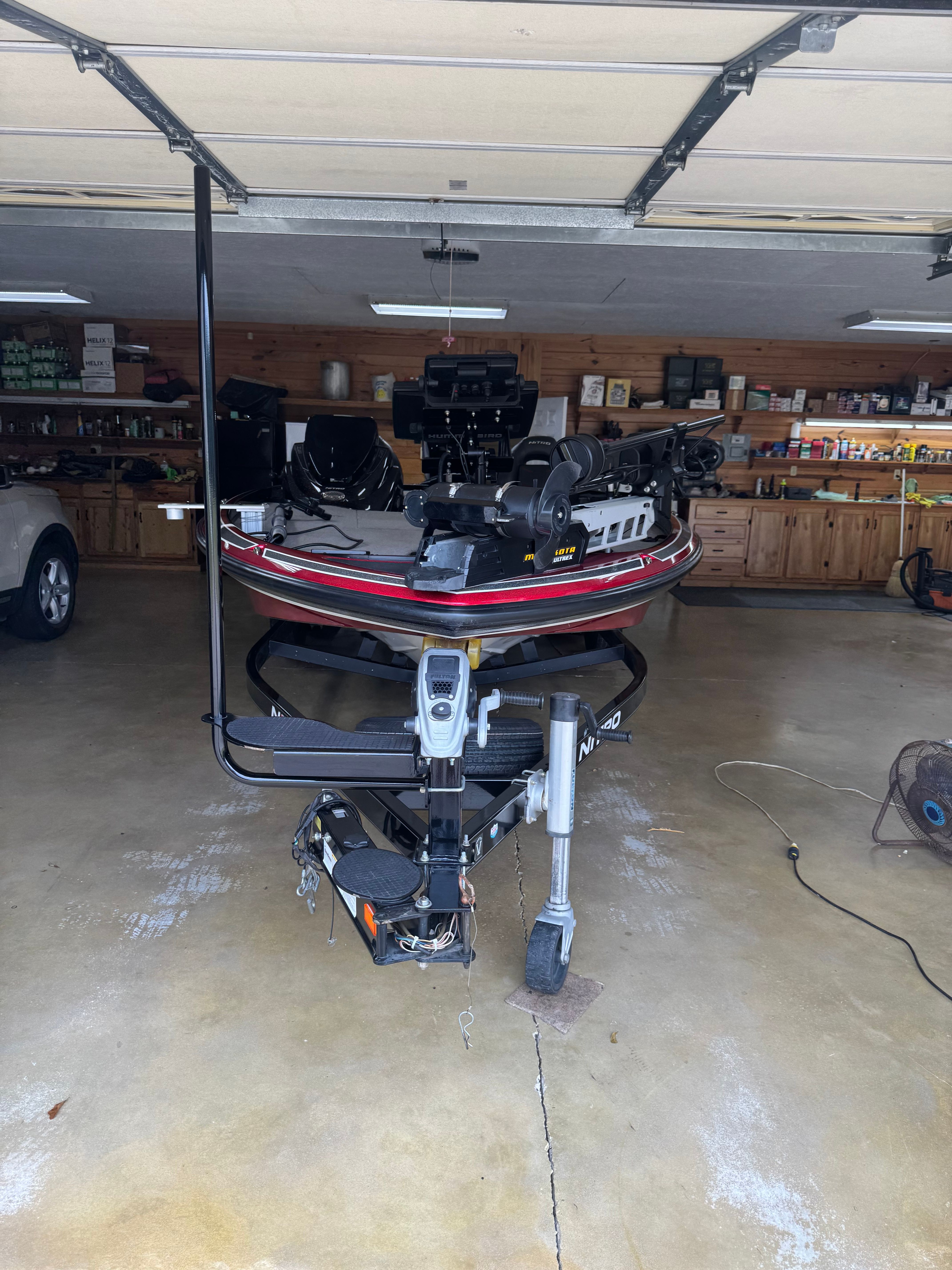 A Nitro Z21 boat is parked in a garage, surrounded by tools and shelves.