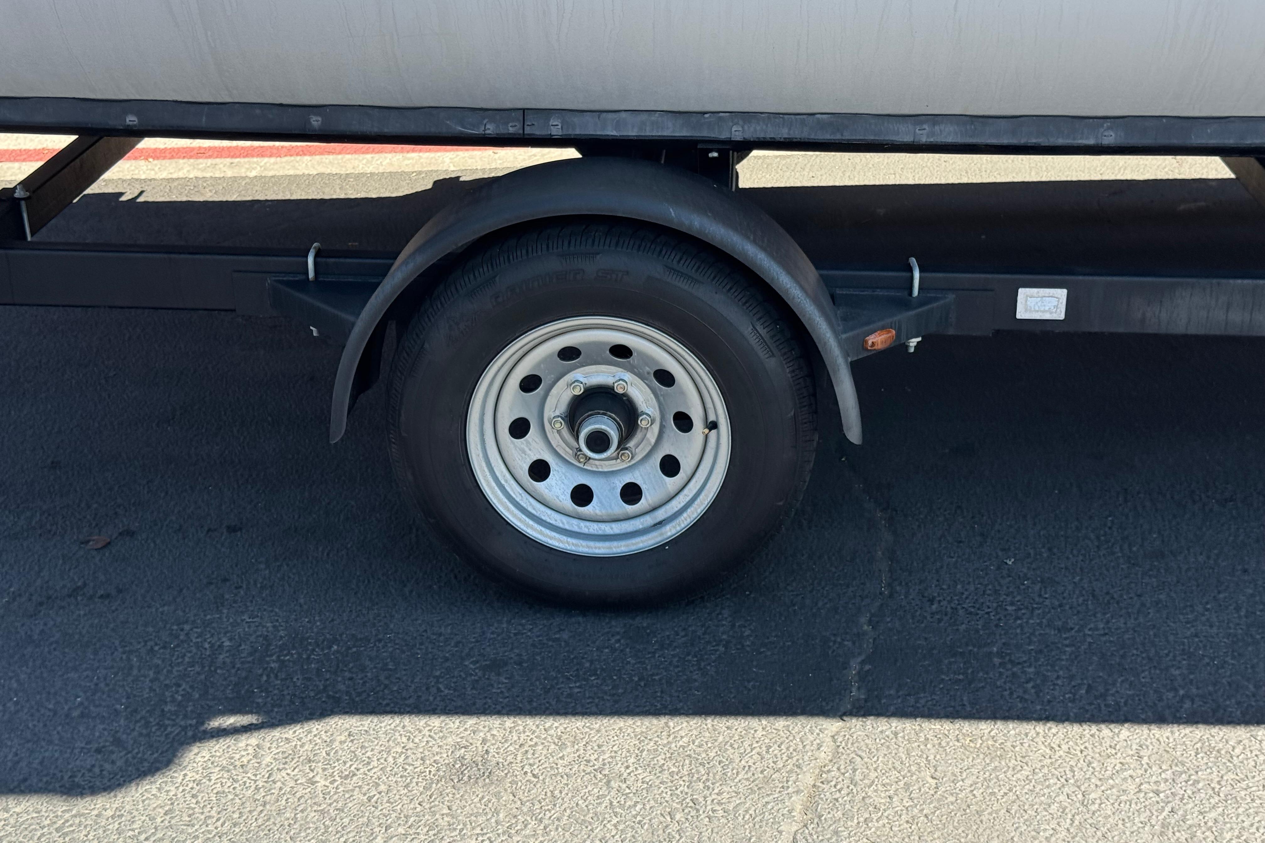 Trailer wheel of 2021 SunCatcher Select 20RCX on asphalt pavement.