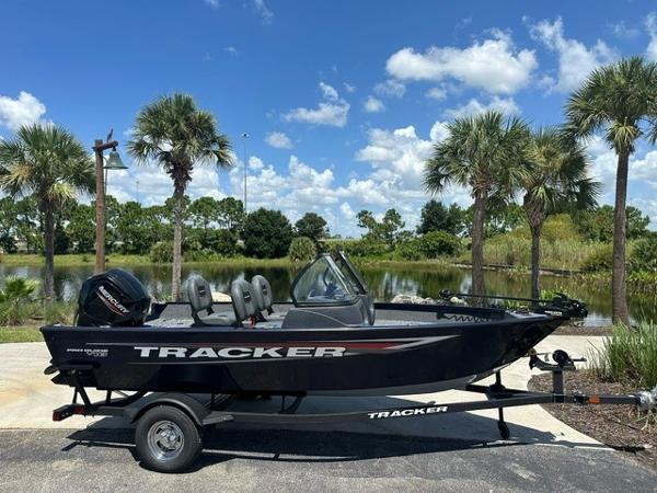 2025 Bass Tracker PGV16WT boat on trailer, parked near palm trees and a pond.