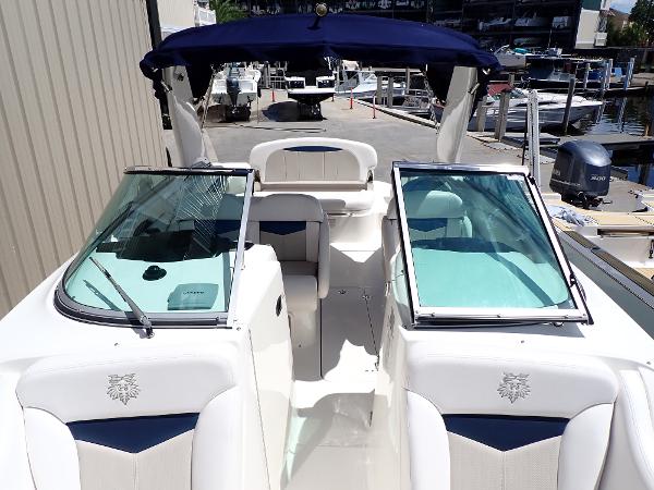 2011 Chaparral 287 SSX boat with open cockpit, white seating, and blue canopy at marina.