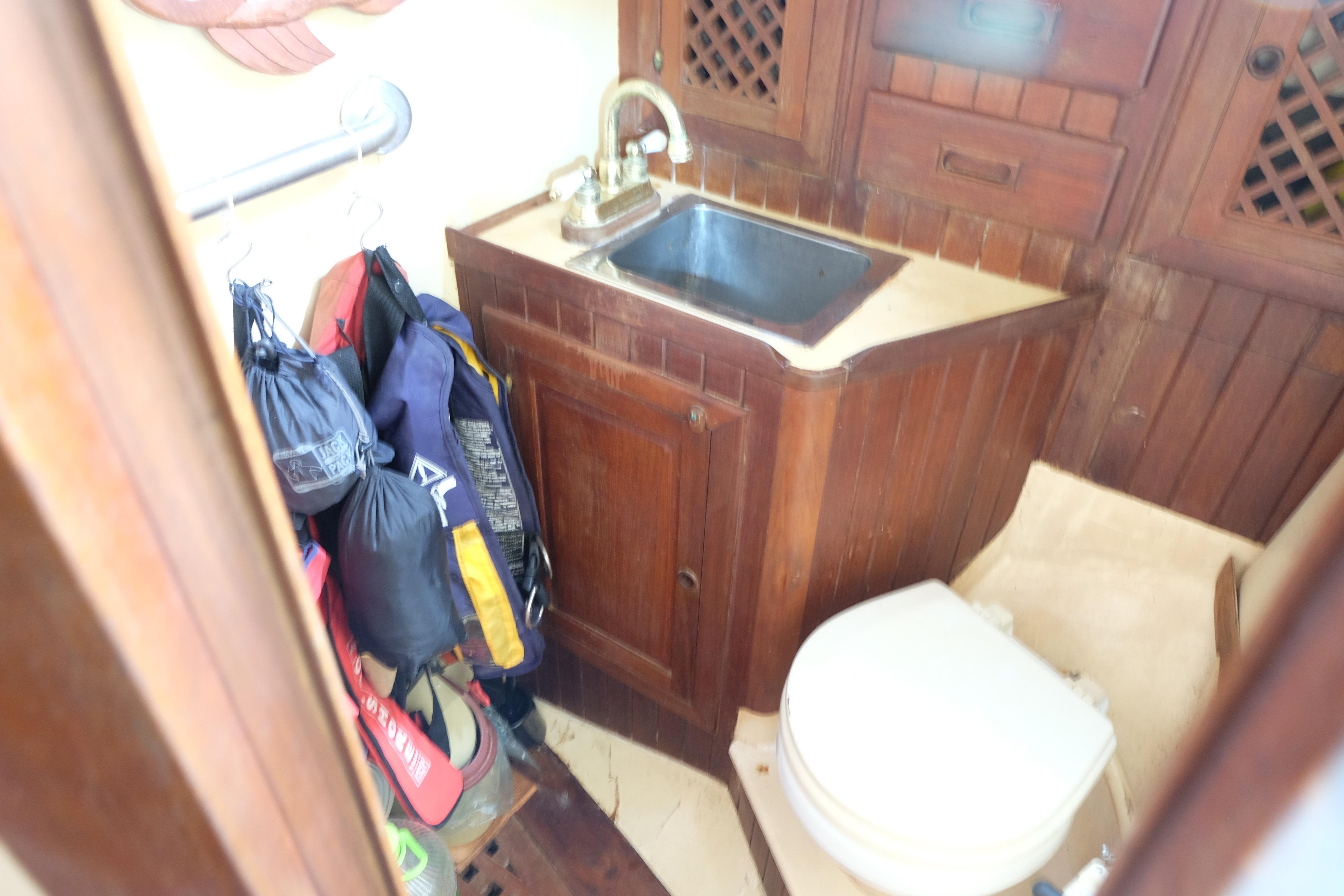 1979 Westwind 35 yacht bathroom with wooden cabinetry, sink, and toilet.