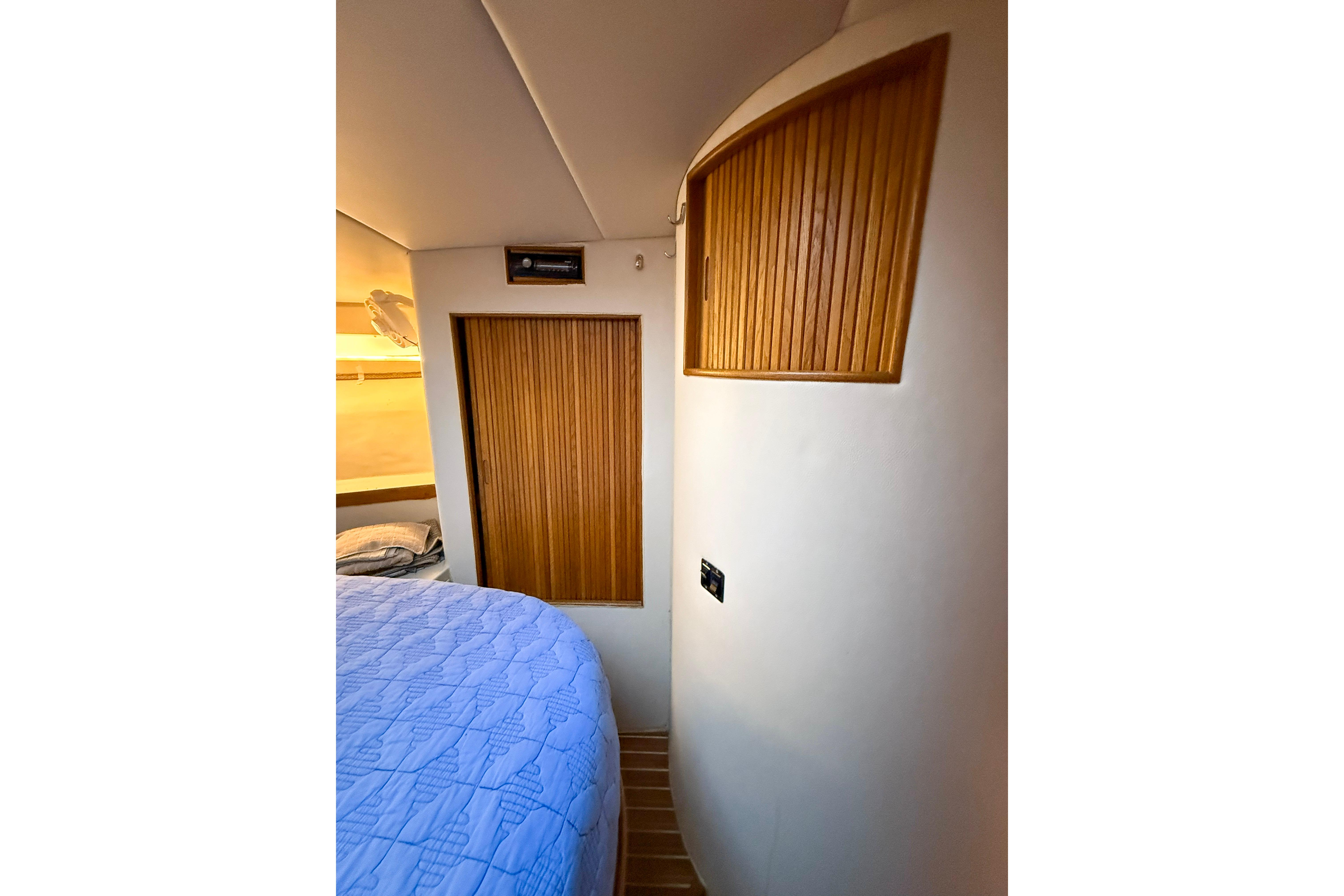 Interior of 1987 Bertram 37 Convertible yacht with wooden accents and blue bedding.