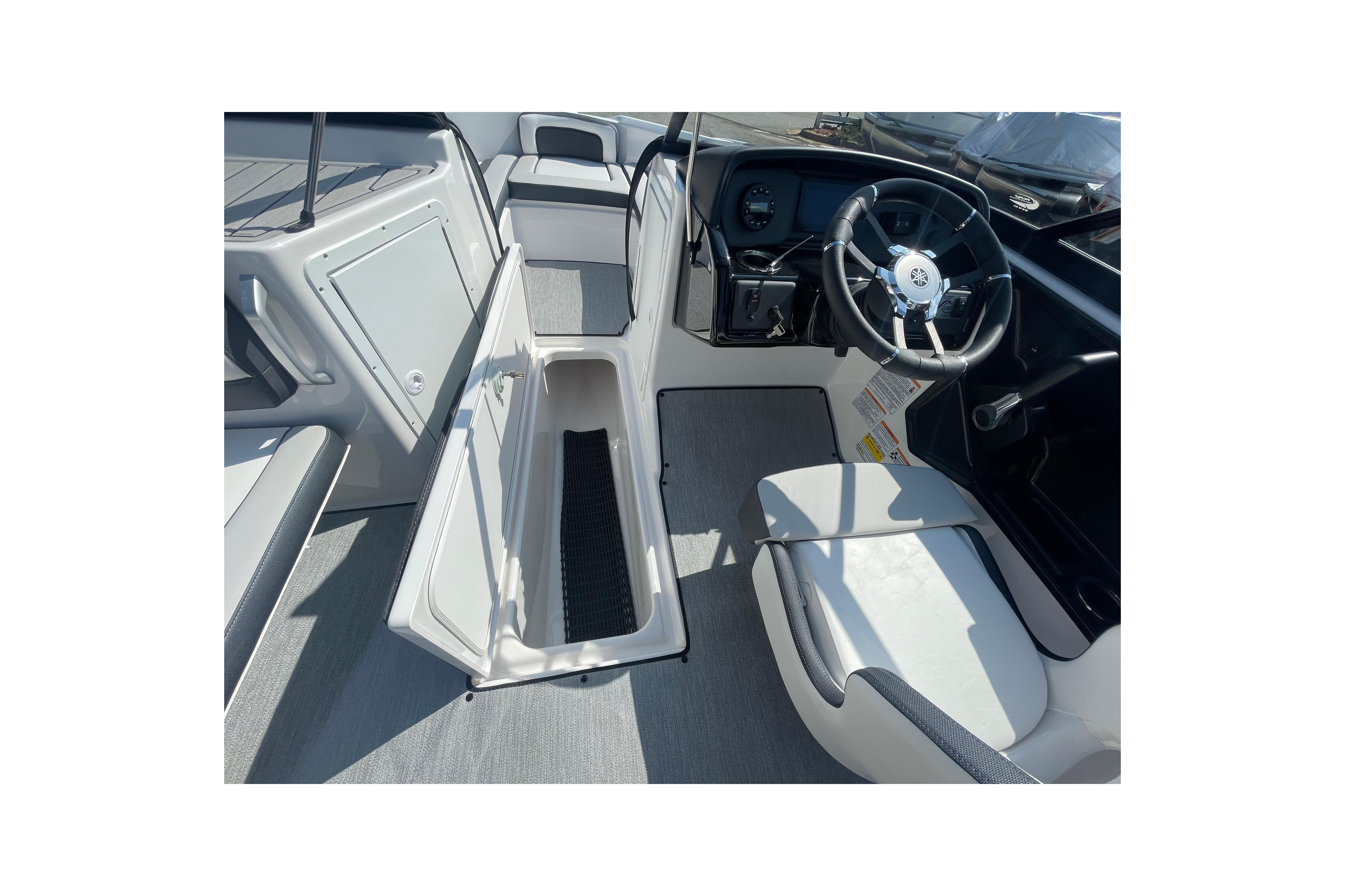2026 Yamaha Boats AR195 interior with open storage compartment and steering wheel.