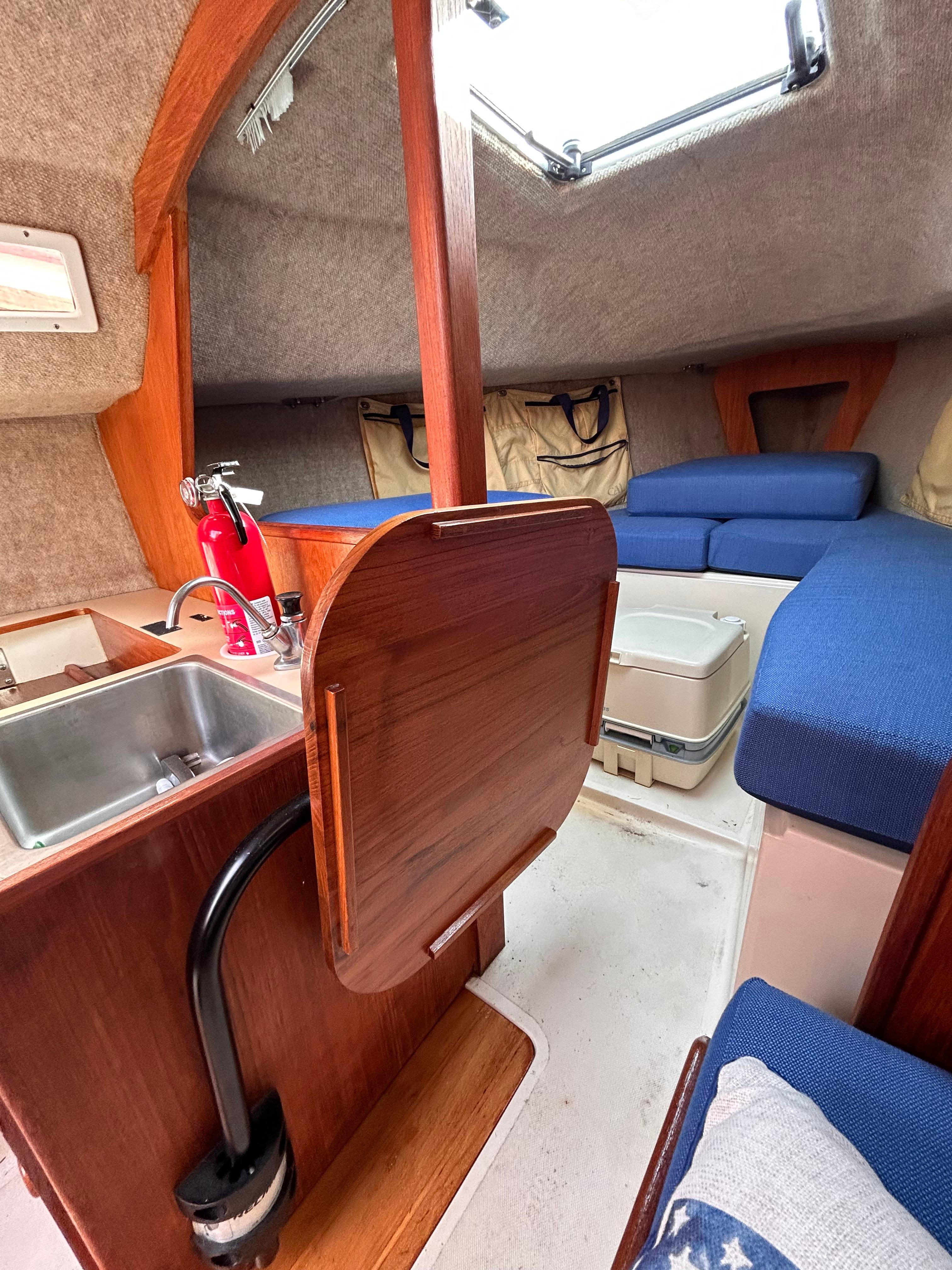 Interior of 1986 CAL 22 sailboat with kitchenette, seating, and storage.