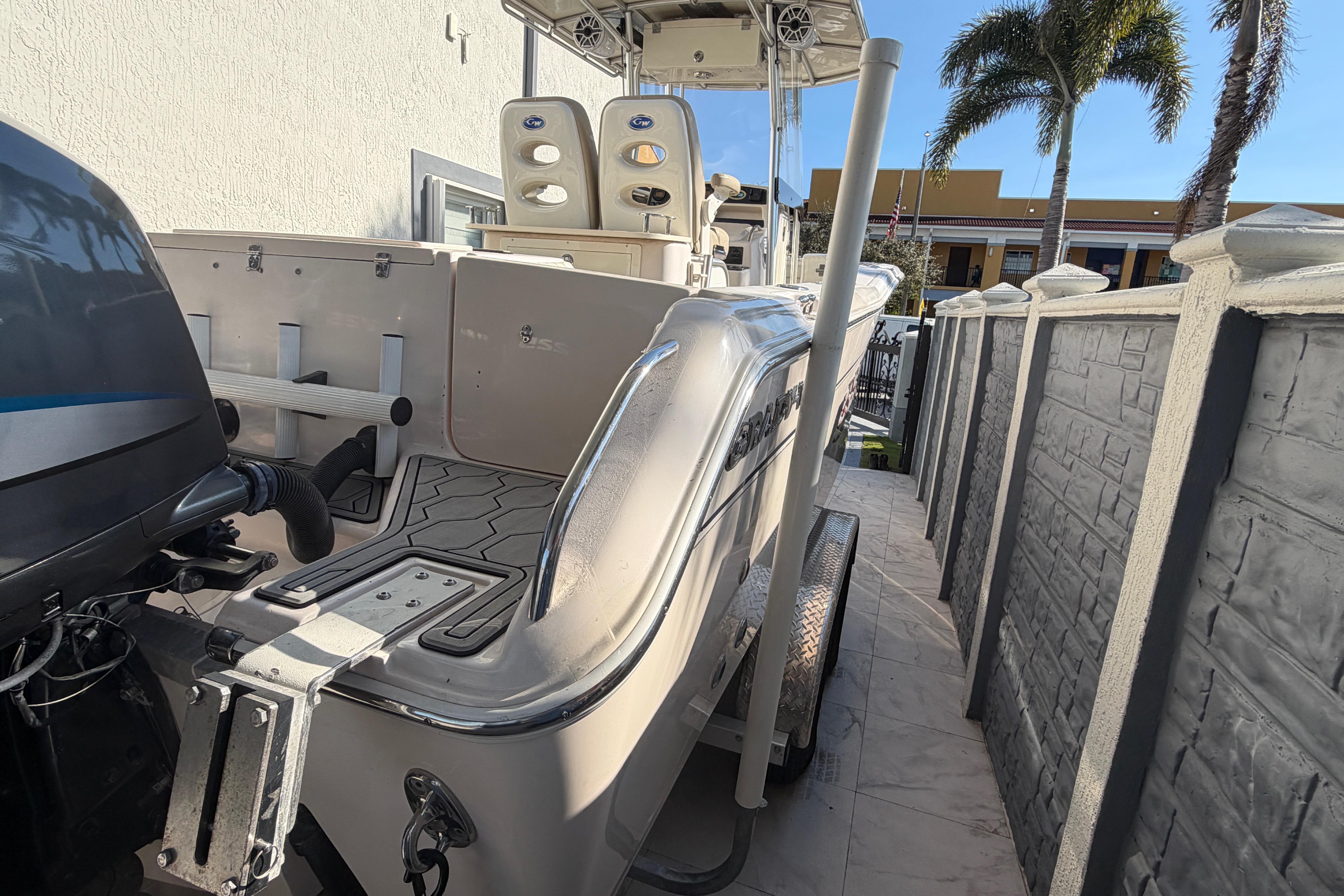 2004 Grady White 273 boat parked beside a wall with palm trees in the background.