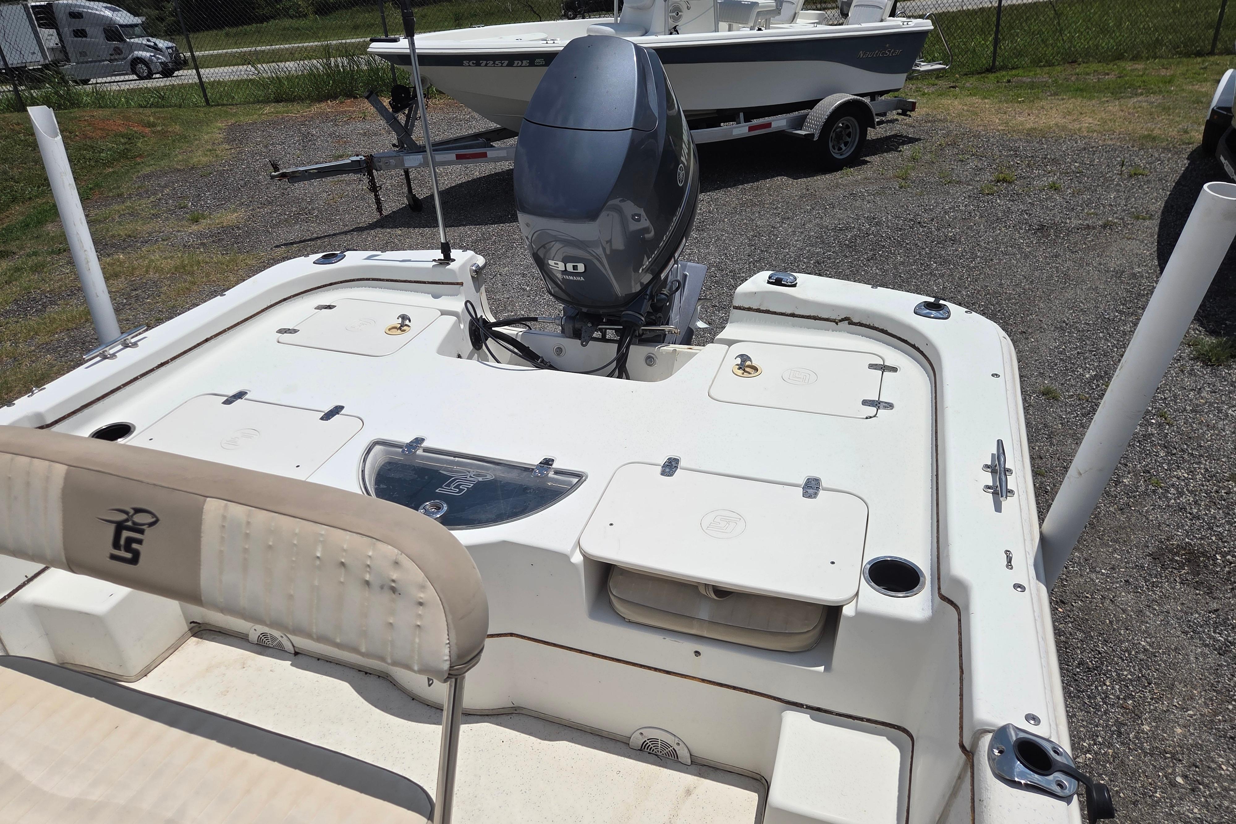 2016 Carolina Skiff 198 DLV boat with outboard motor, parked on gravel lot.