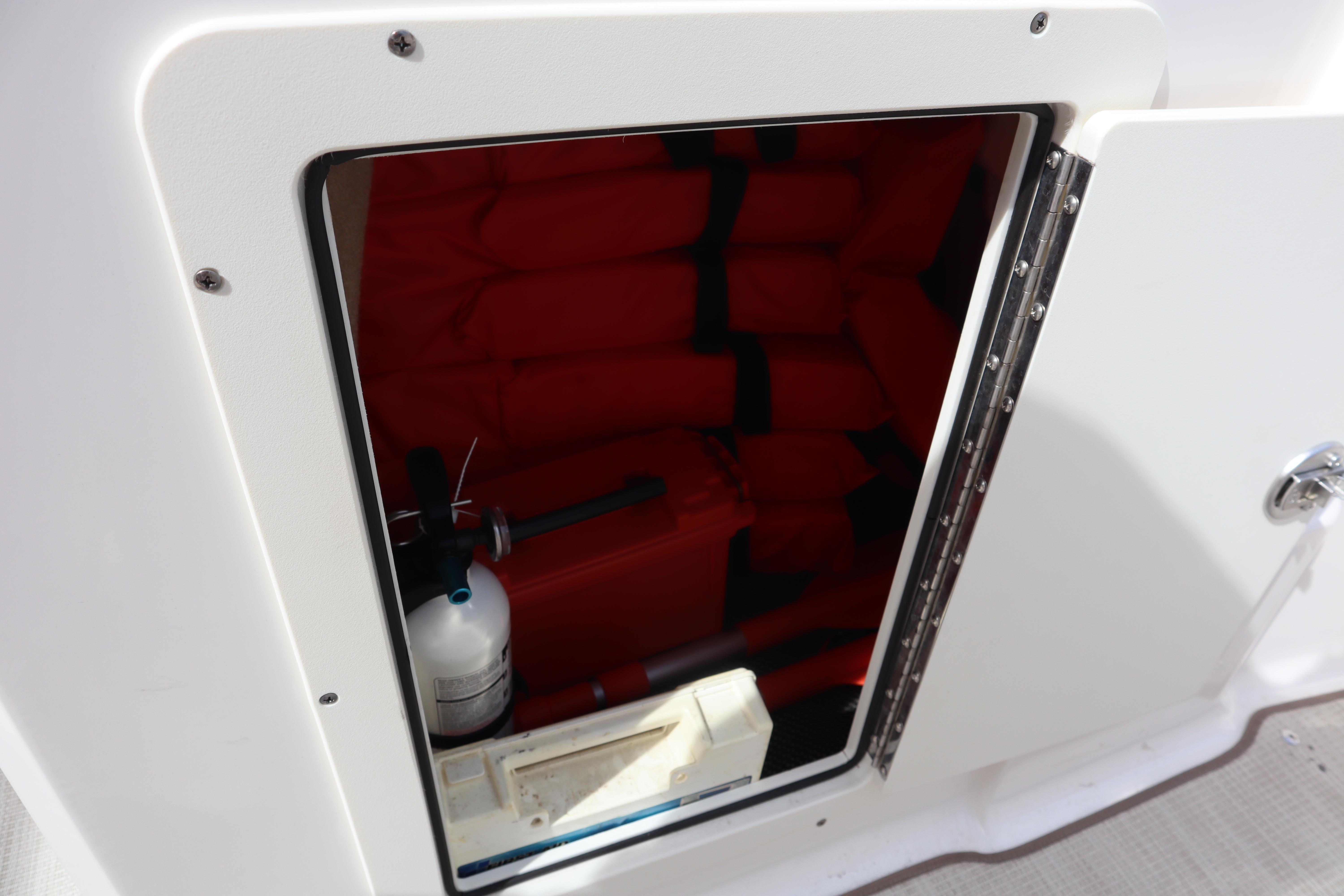 Storage compartment on a 2021 Chaparral 21 SSi boat with life jackets and fire extinguisher.