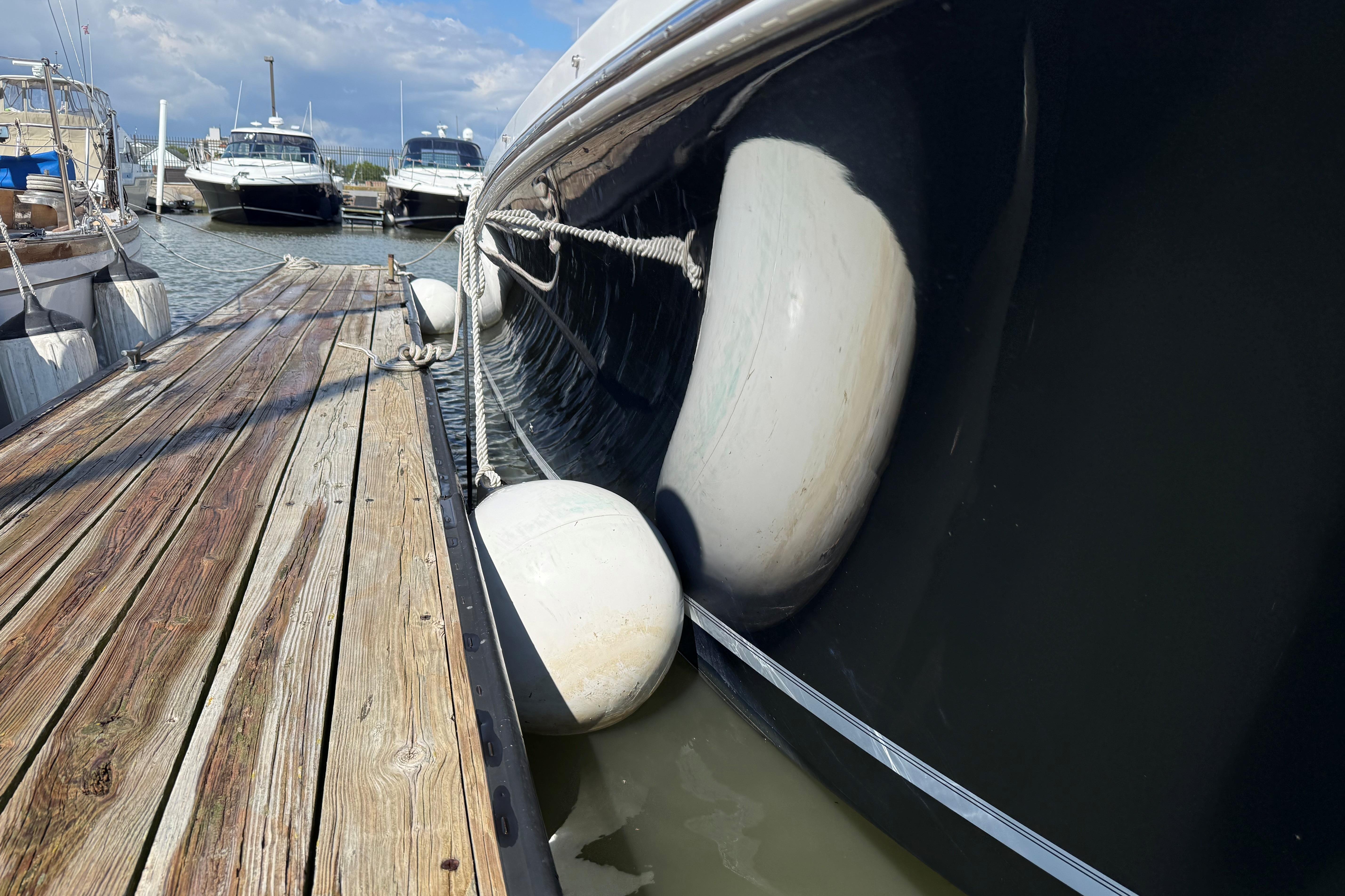 2019 Regulator 34SS boat docked with fenders, wooden pier, and other boats in background.