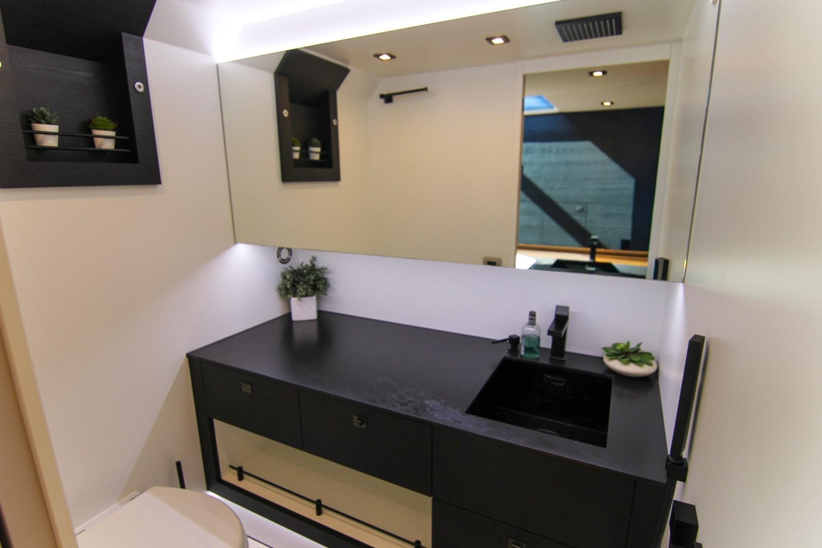 Modern bathroom interior on 2022 Vanquish Yachts VQ45, featuring sleek black countertop and mirror.