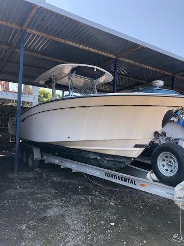 2006 Grady-White Bimini 306 boat on trailer under metal shelter.