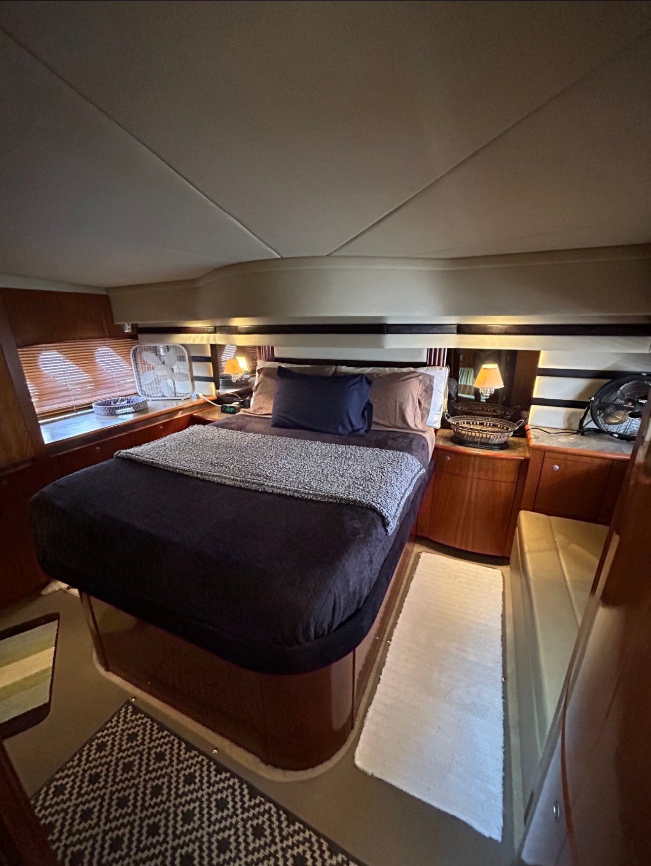 Luxurious bedroom with double bed, wooden furnishings, and soft lighting in a yacht cabin.