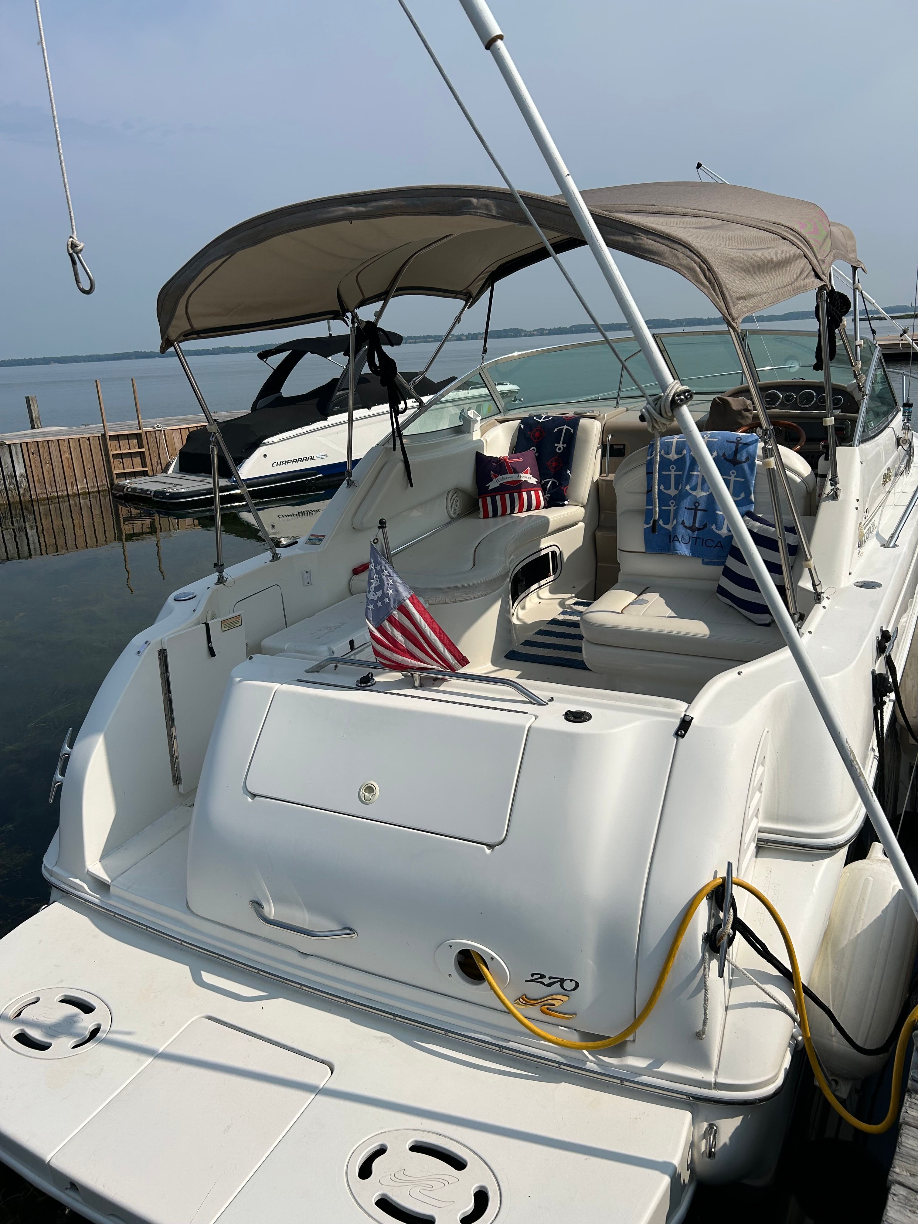 A 1999 Sea Ray 270 Sundancer at the dock, featuring a sunshade and cozy seating area.
