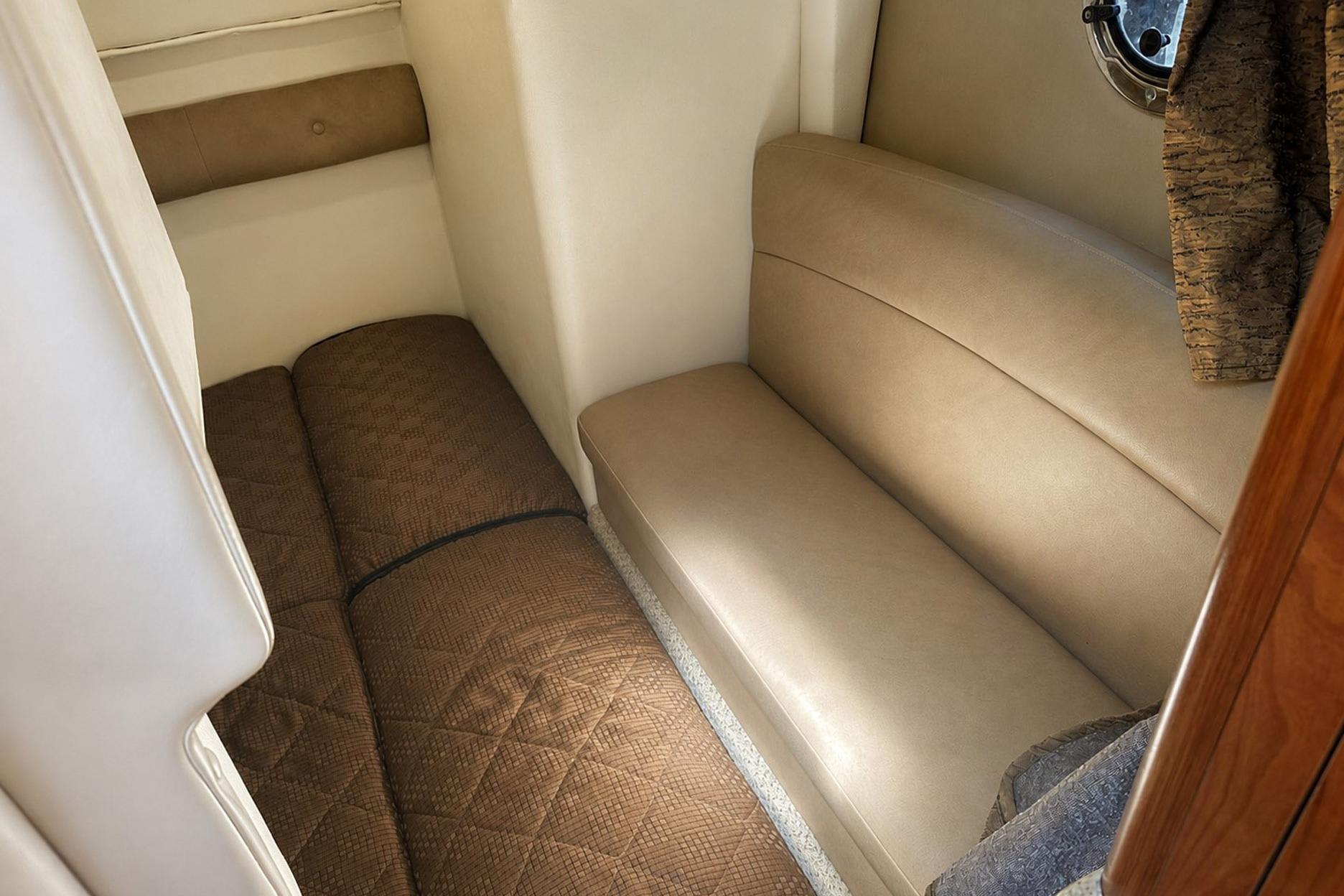 Interior cabin of 2012 Rinker 310 Express Cruiser LE with beige seating and brown bedding.