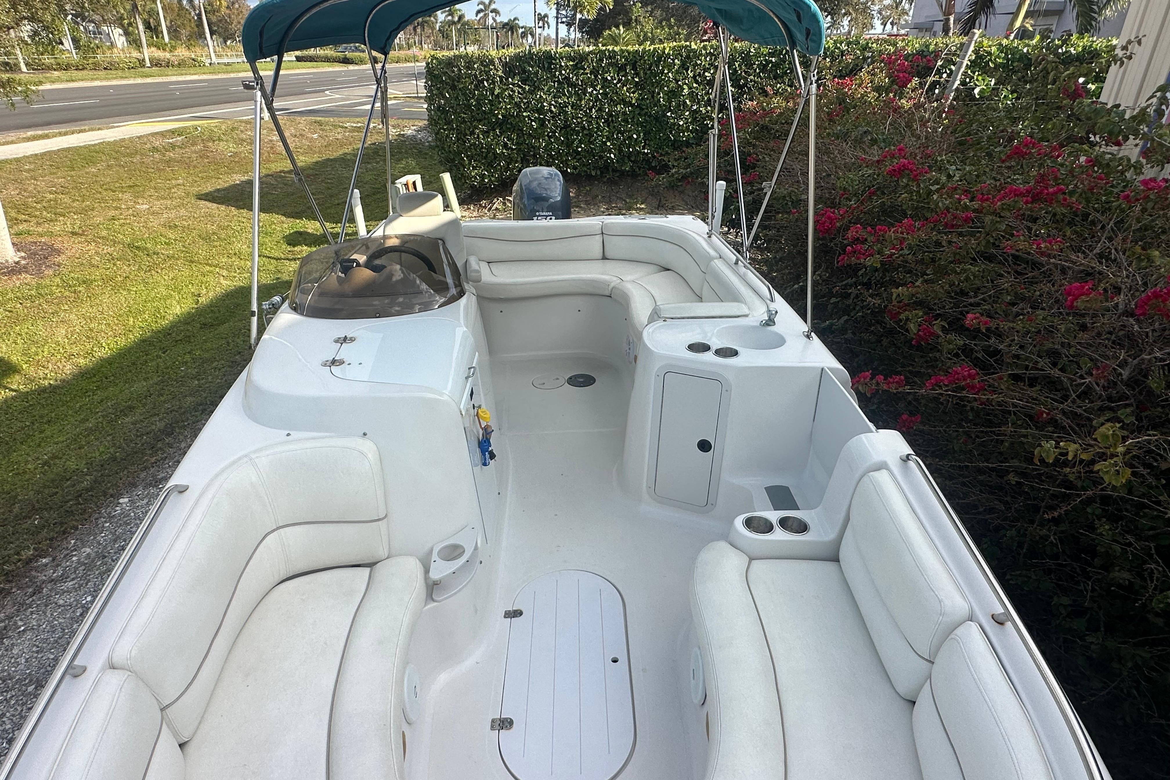 2004 Vectra S-215 boat with white seating and canopy, parked near greenery.