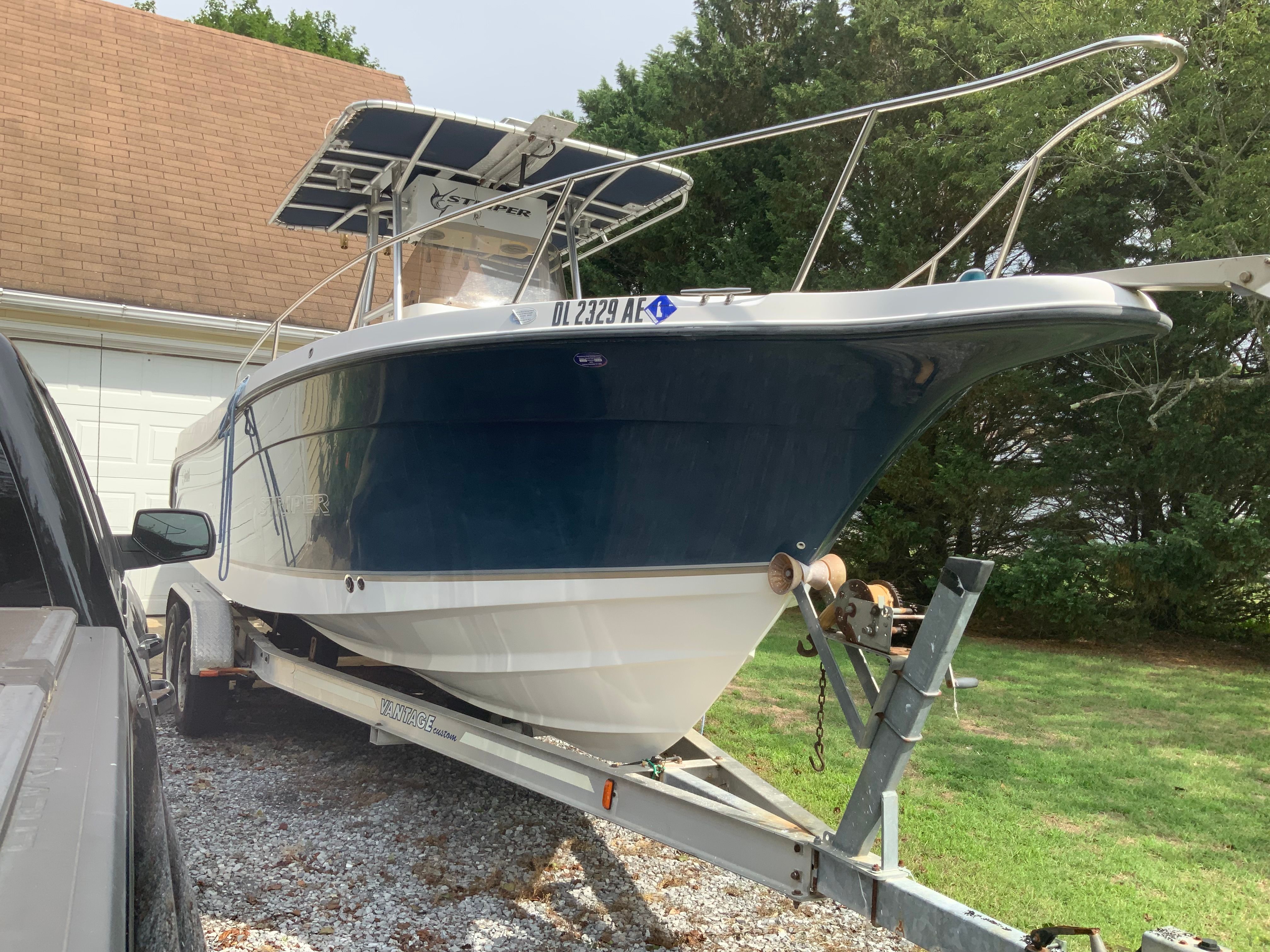 A 2006 Seaswirl Striper 26 on a trailer, parked next to a house.