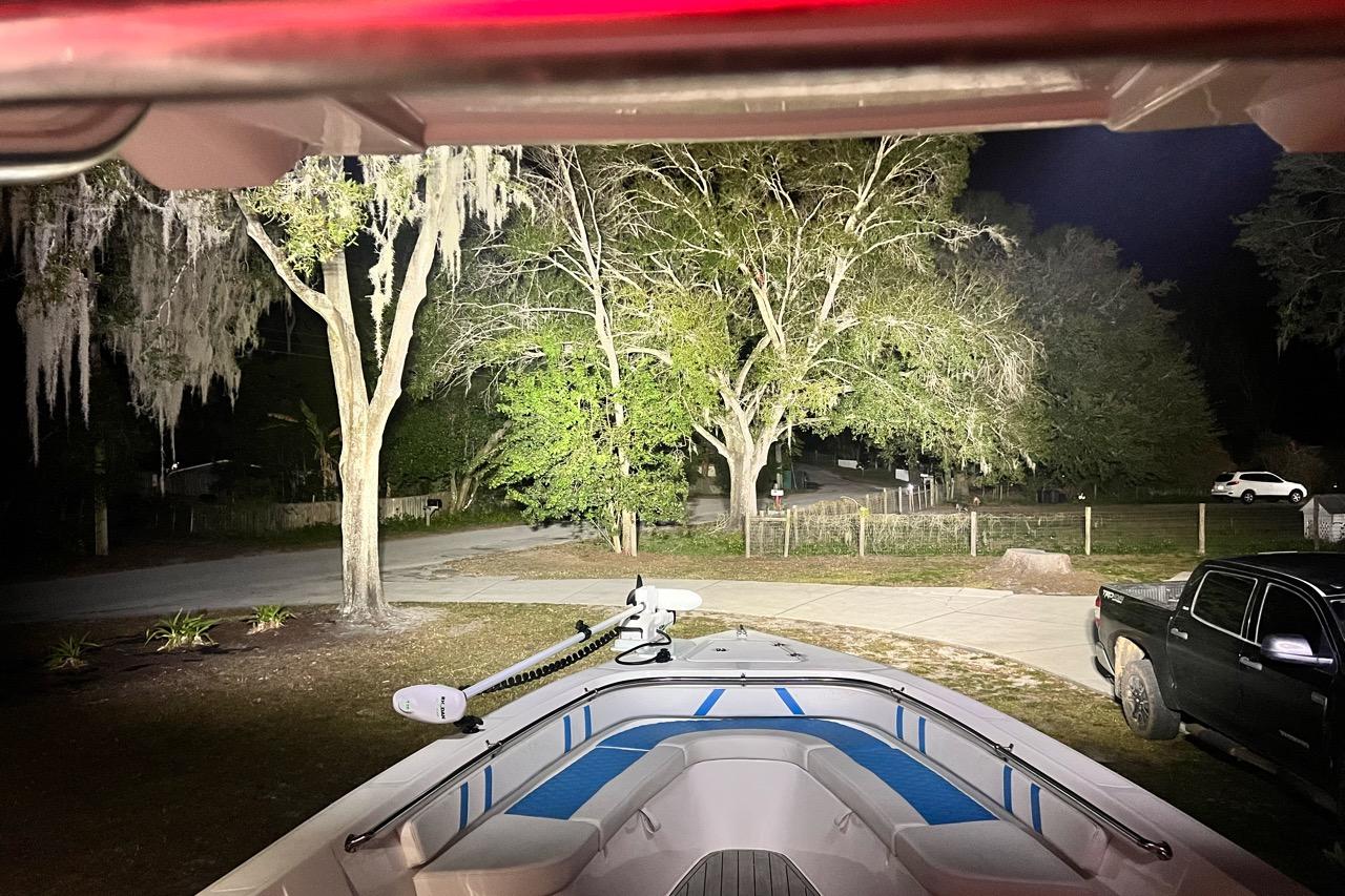 Custom Infusion 34 CC boat parked at night, illuminated by bright lights, with trees in the background.