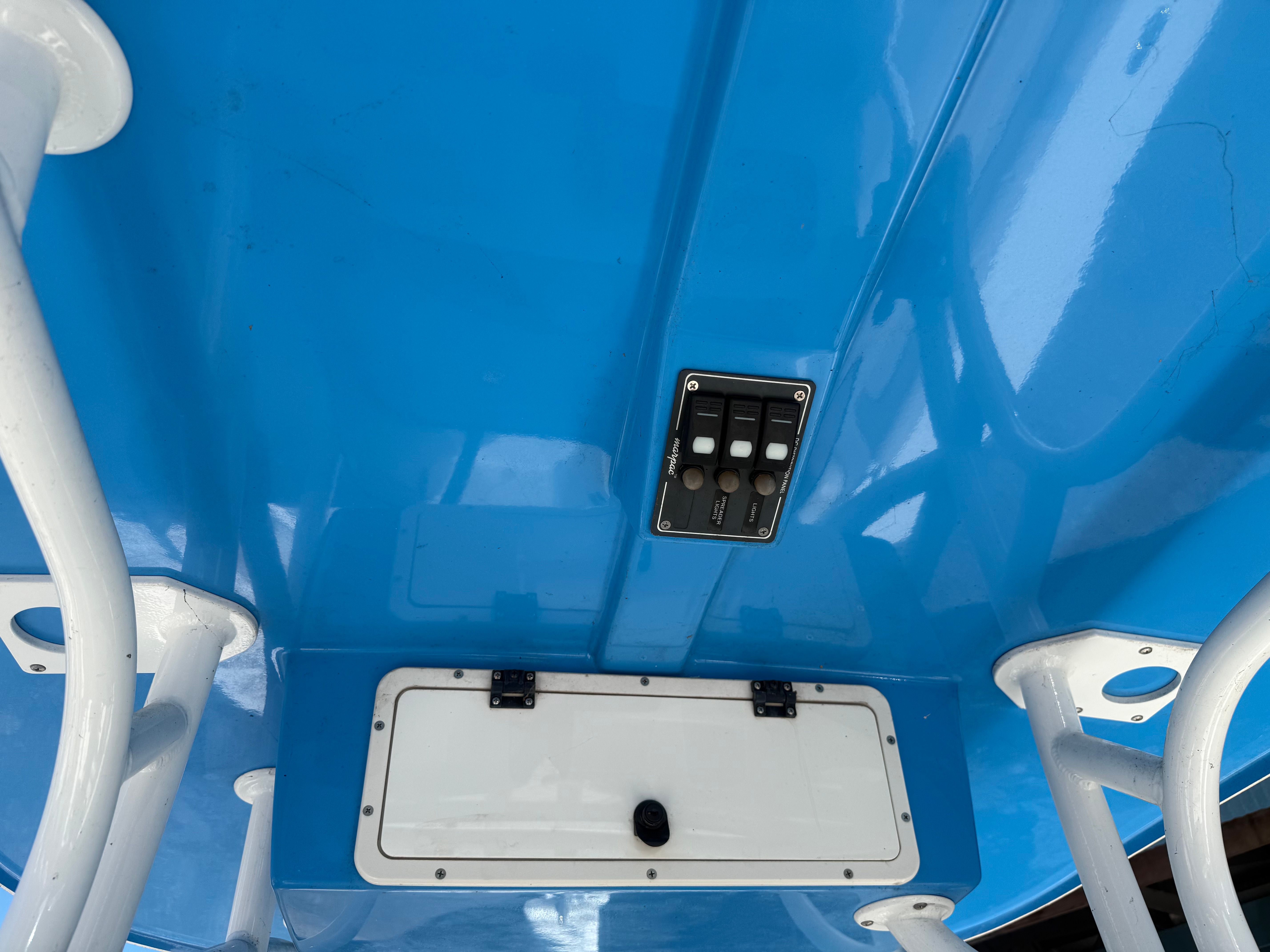 View of a boat's blue ceiling with switches and a compartment.
